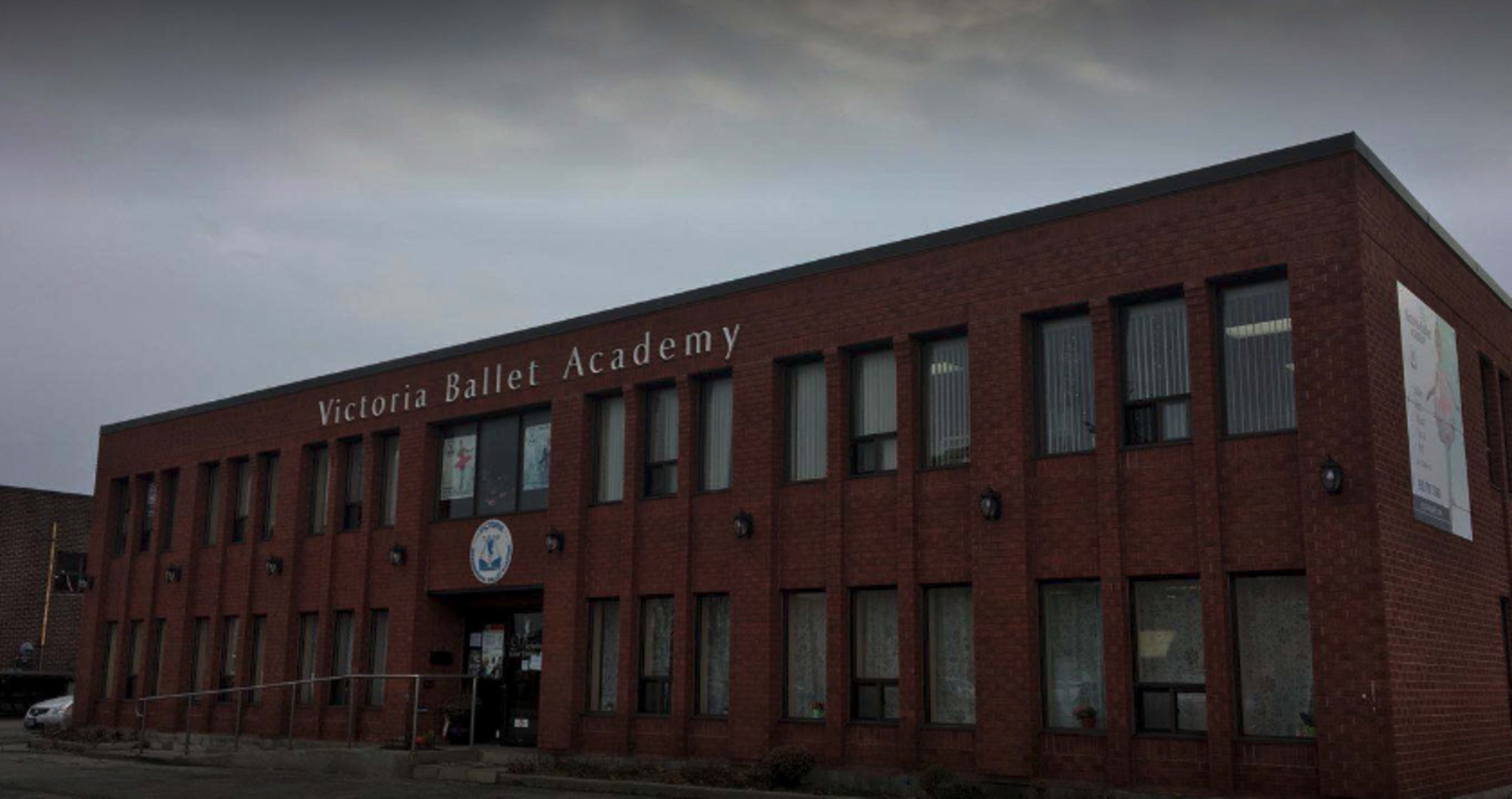 A brick building with large windows, prominently featuring the sign "Victoria Ballet Academy" above the entrance.