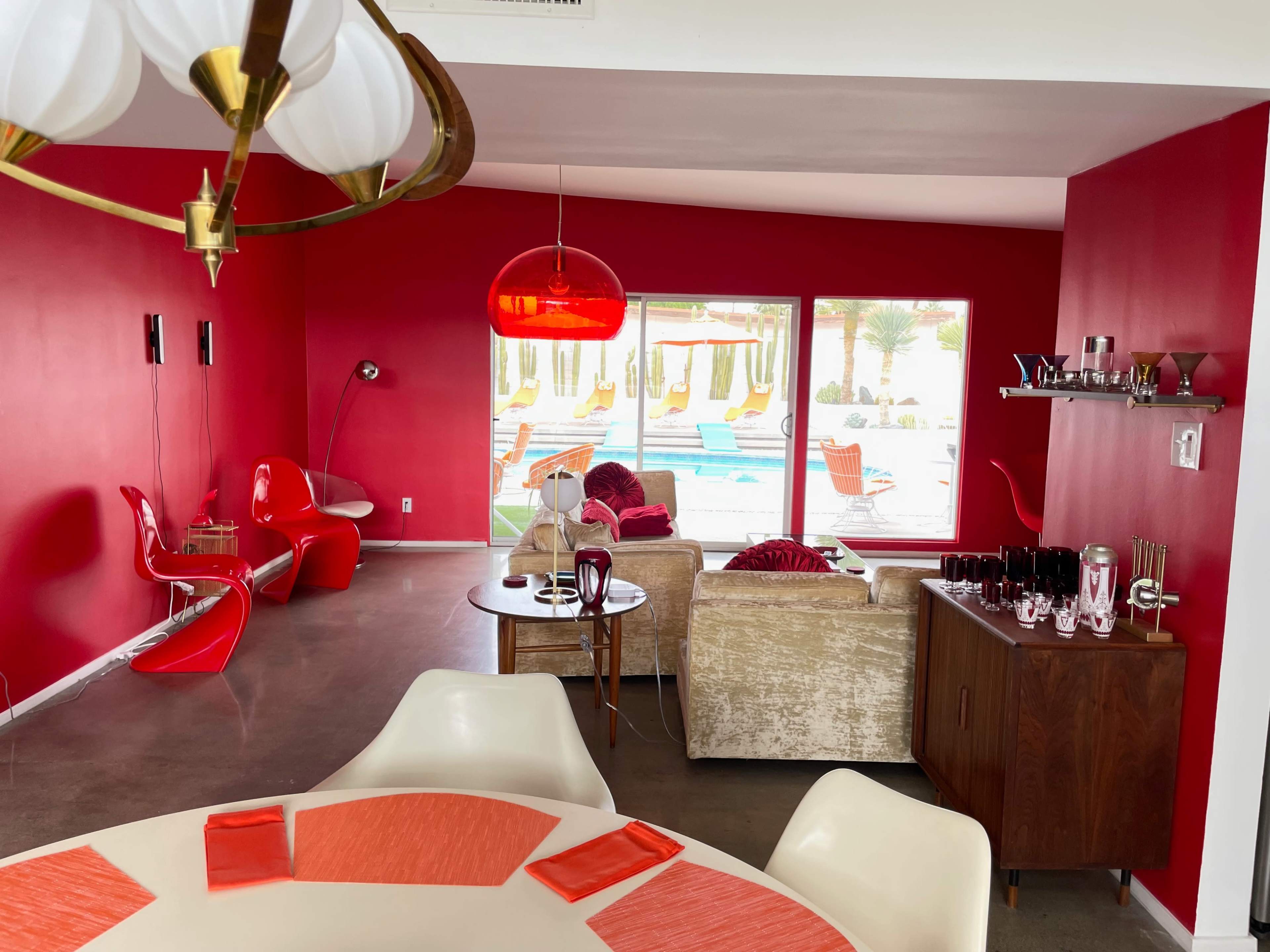 A modern interior featuring red walls, contemporary furniture, and a view of a pool area through large glass doors.