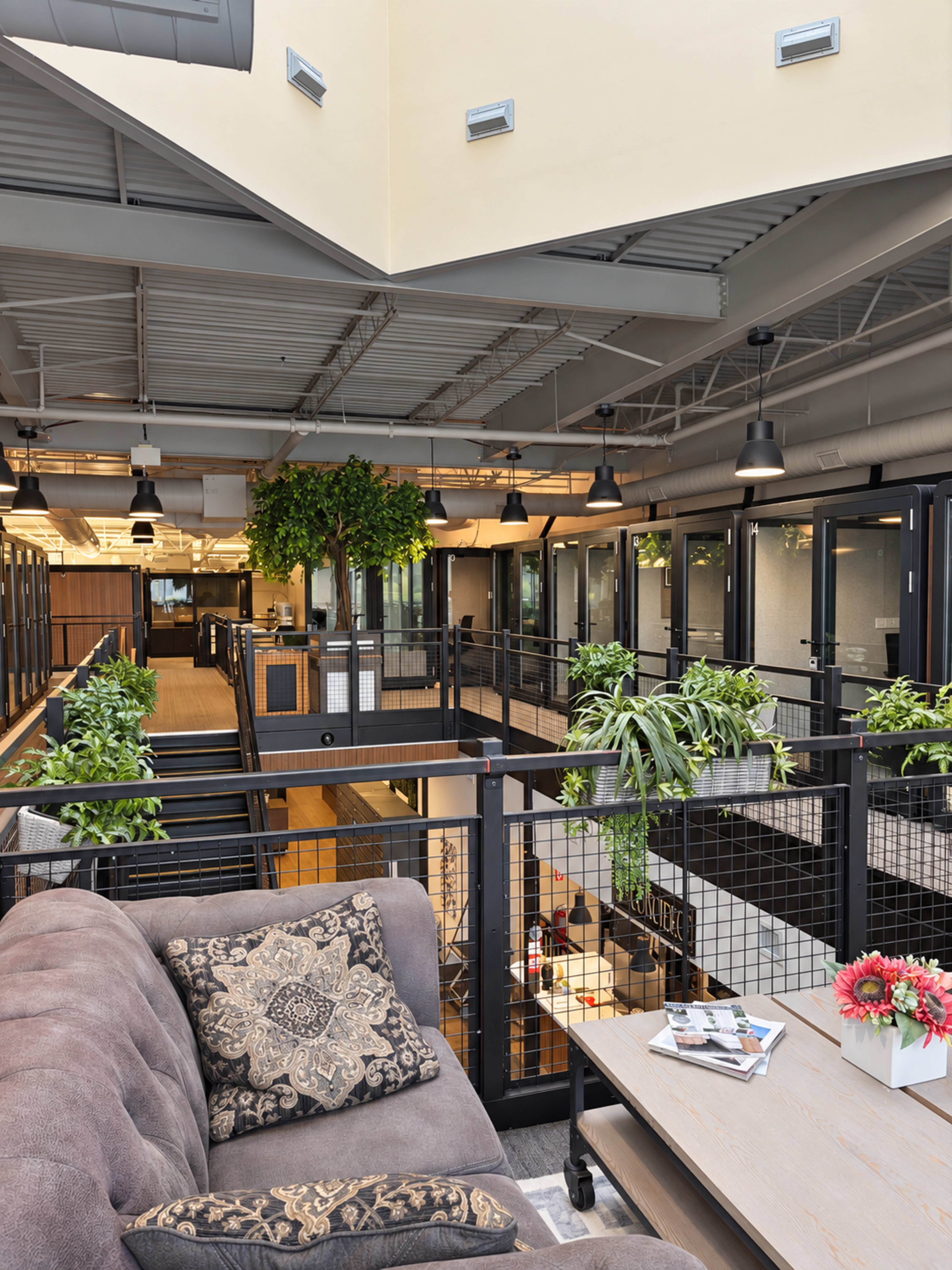 The image shows a modern office interior with multiple floors, featuring a lounge area with a sofa, greenery, and open workspaces separated by glass partitions.