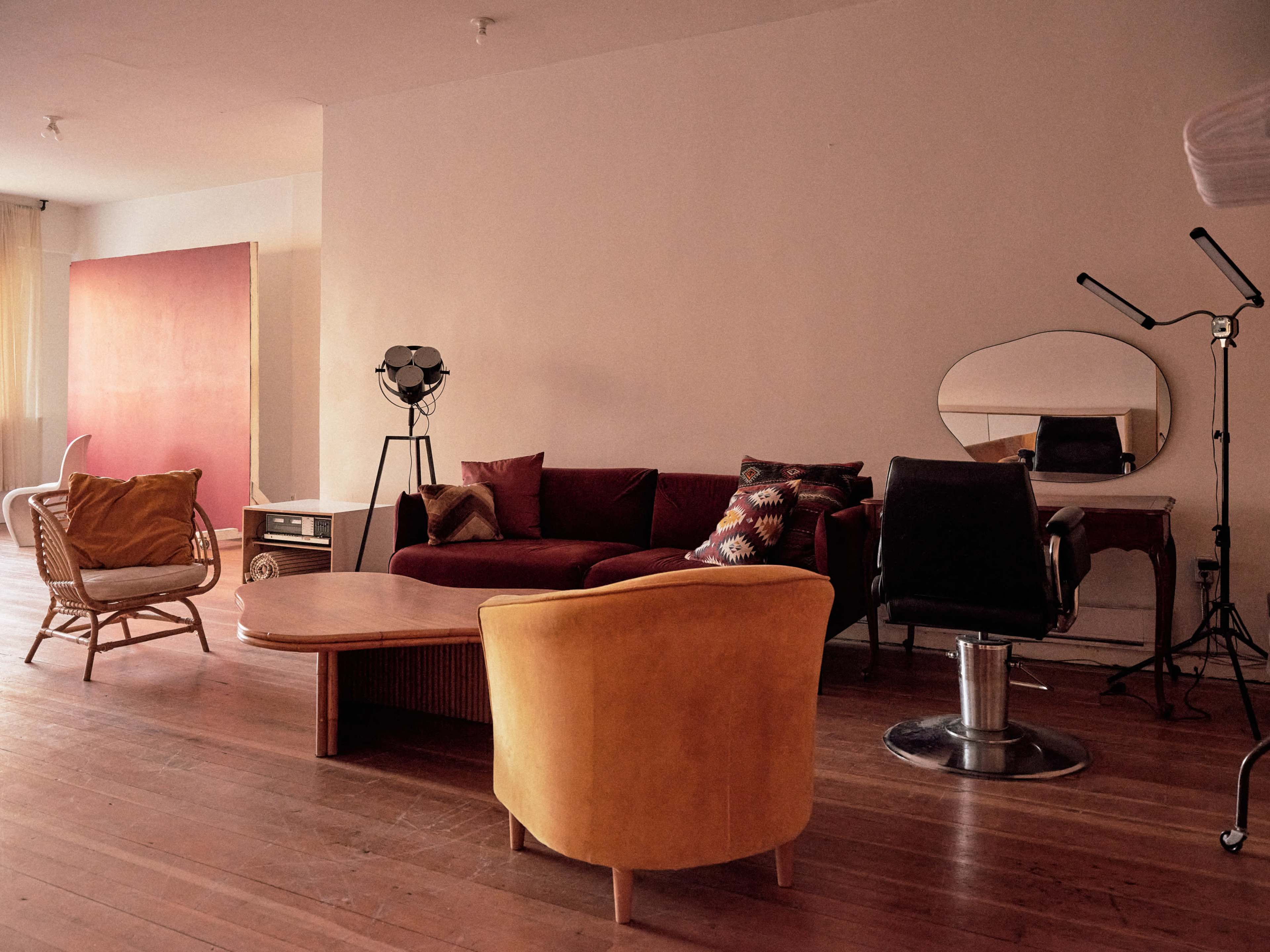 The image shows a modern living room with a mix of furniture, including a red couch, a yellow armchair, and a round coffee table, along with a standing lamp and a wall-mounted mirror.