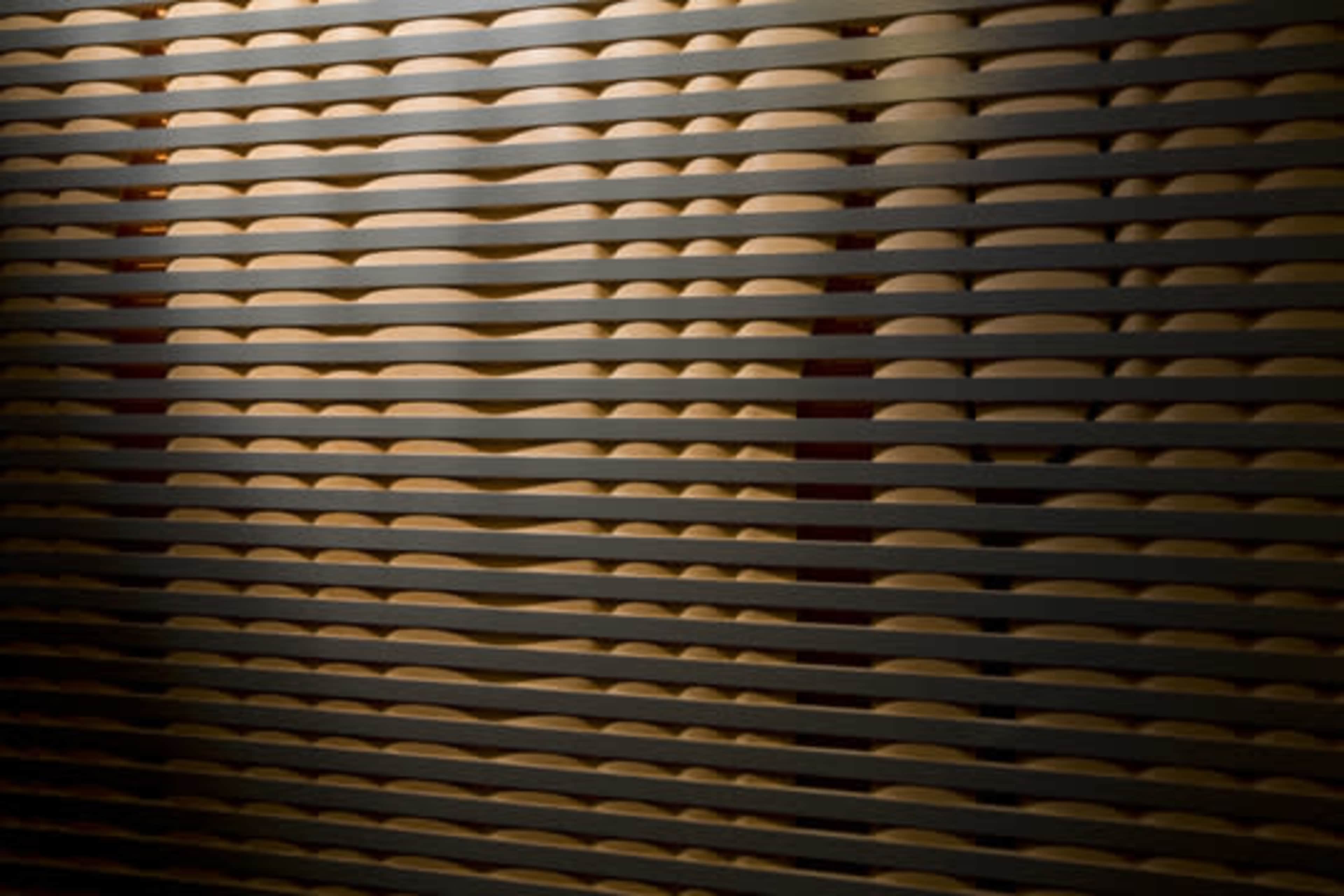 A series of horizontal wooden slats arranged in a parallel pattern, creating a textured surface with alternating light and shadow.