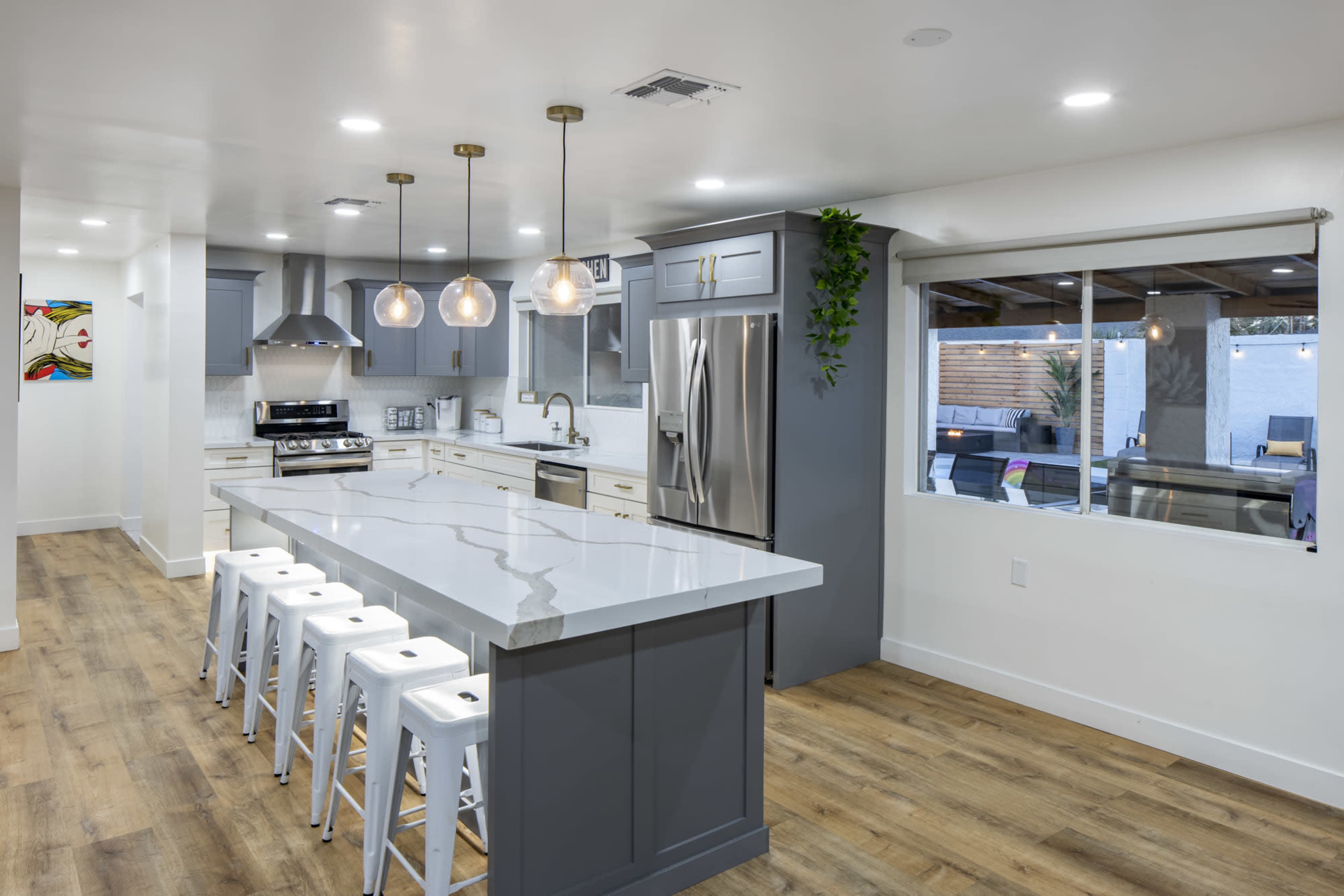 The modern kitchen features a large island with bar stools, stainless steel appliances, and a spacious layout with ample natural light.