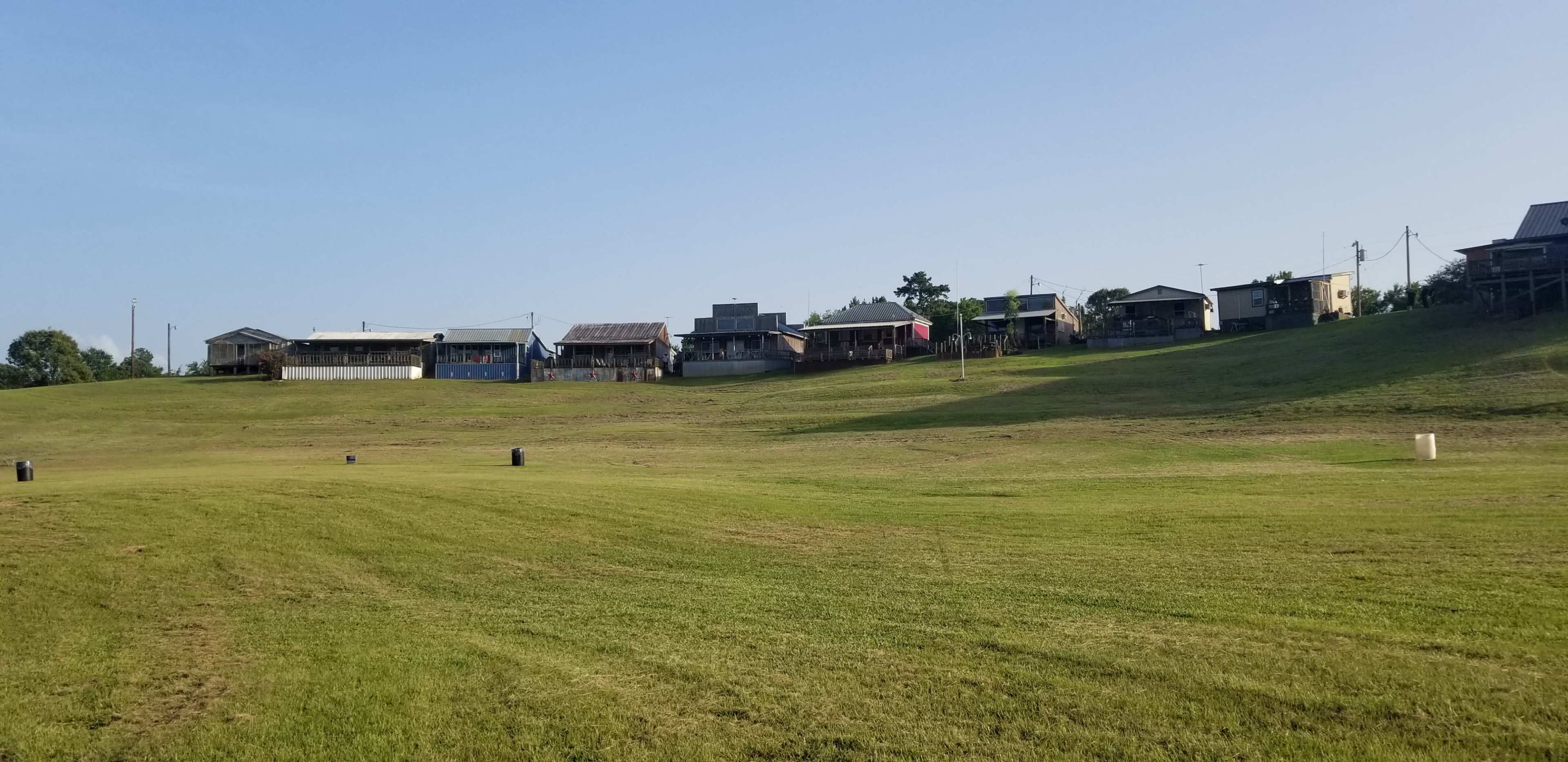 A row of houses lines a grassy hillside under a clear blue sky.