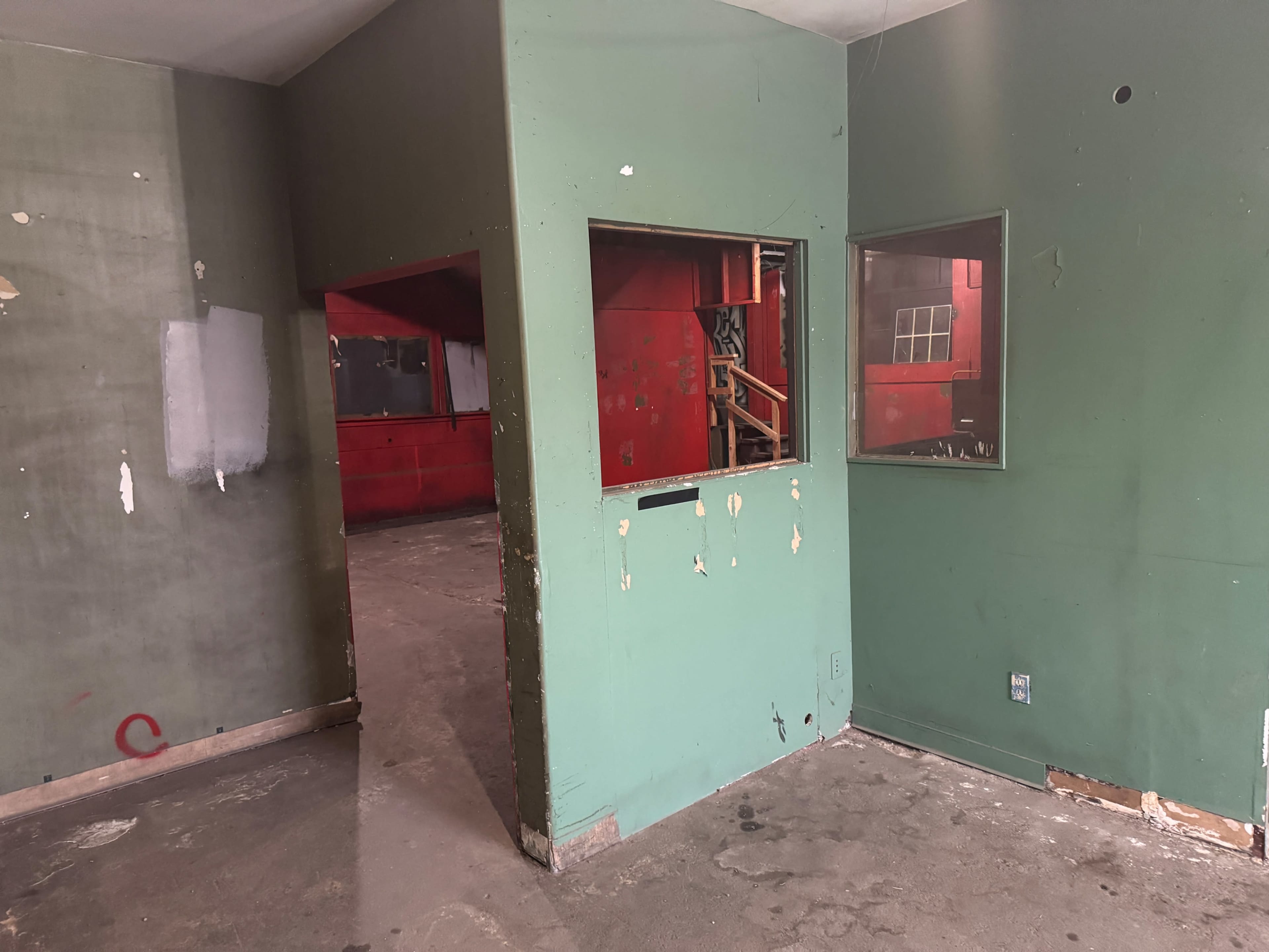 The image shows an empty room with green walls, featuring two openings to adjacent areas and a red wall visible in the background.