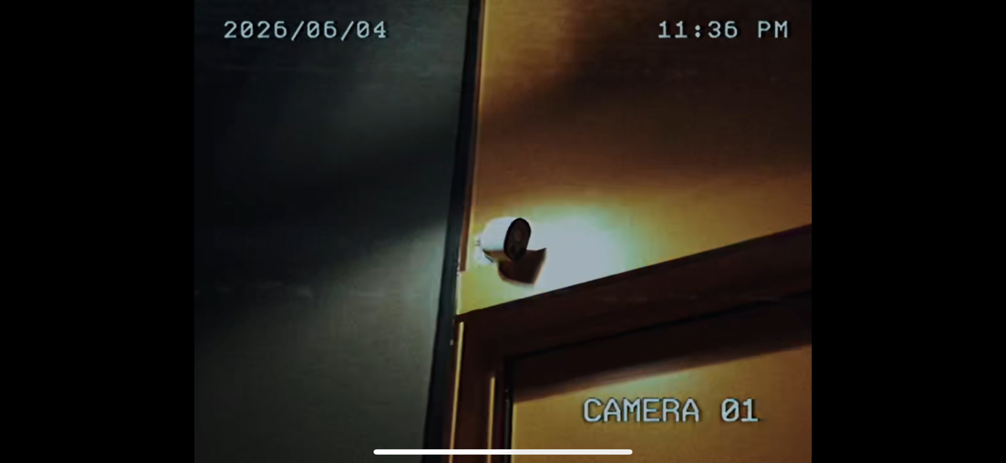 A security camera is mounted in a dimly lit corner near a doorway, displaying a timestamp of 11:36 PM on June 4, 2026.