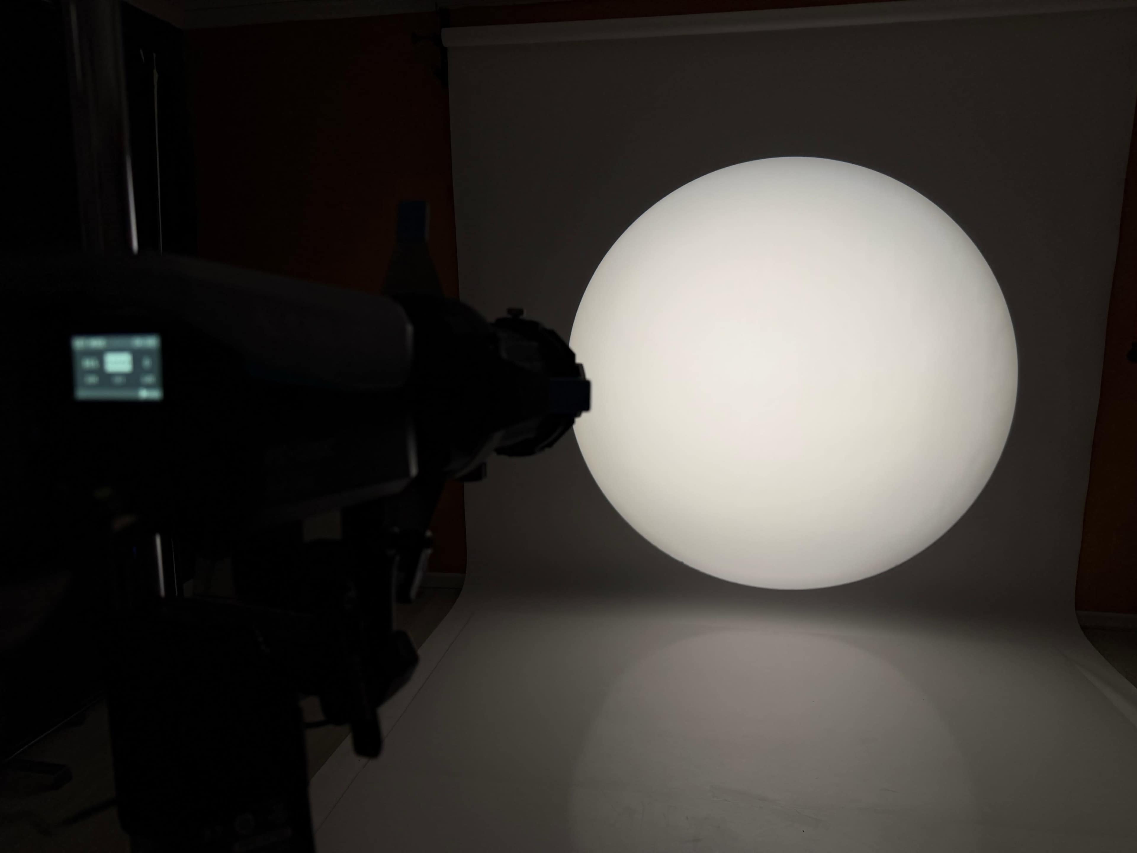A camera is positioned in front of a large, evenly illuminated circular backdrop in a studio setting.