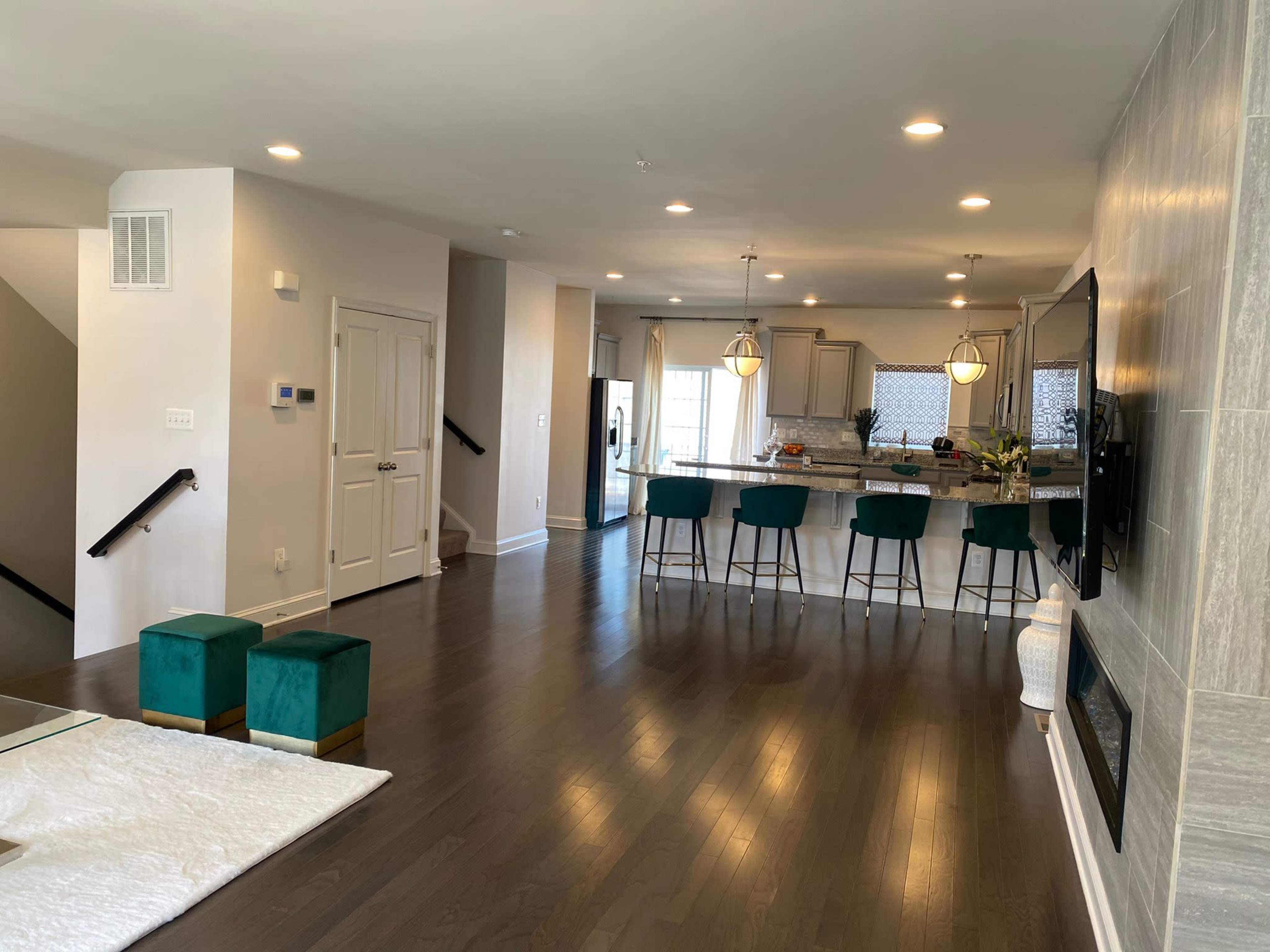 A modern living space featuring a kitchen with bar stools, a dining area, and a cozy sitting area with a decorative throw.