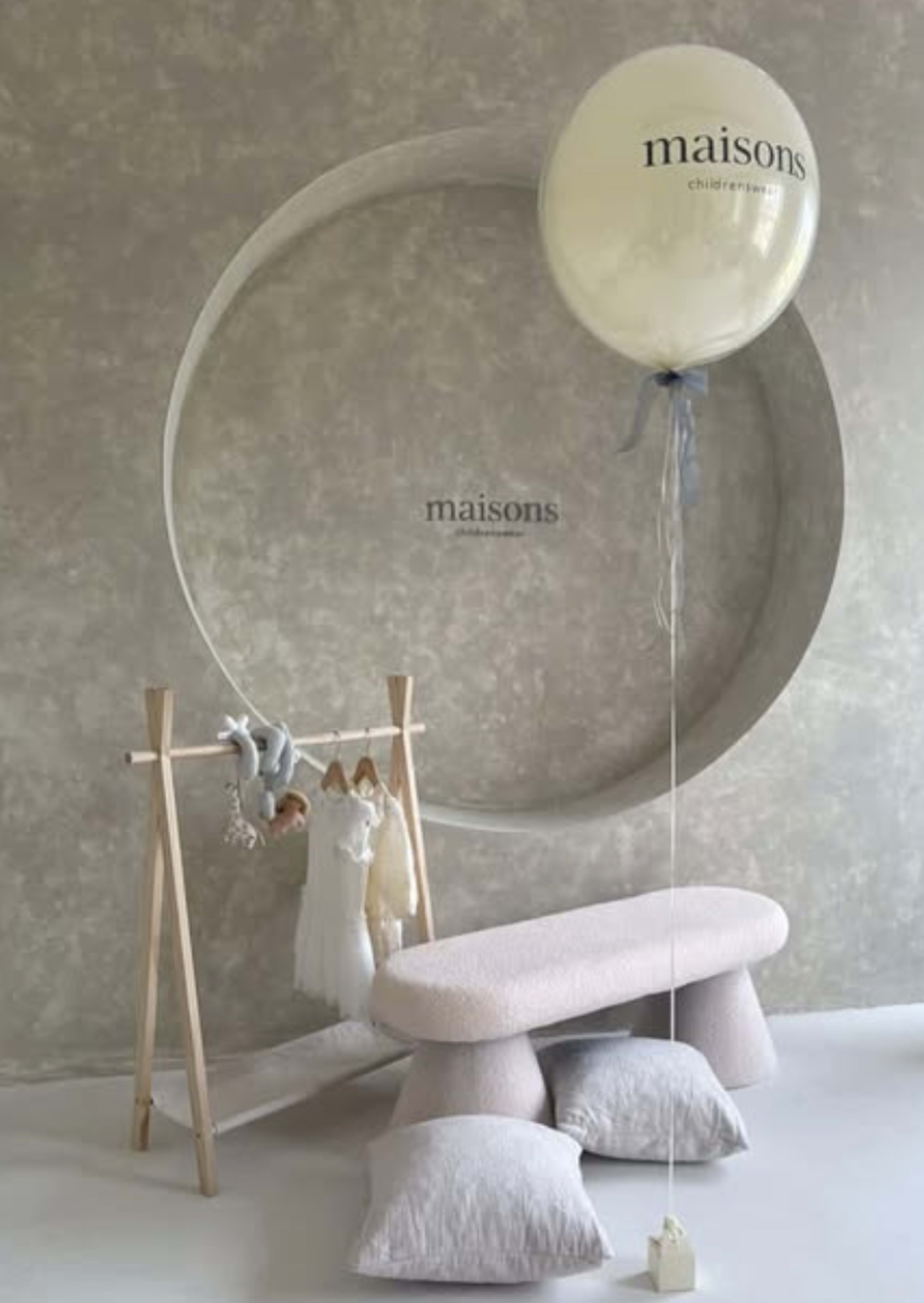 A minimalist children's room features a circular wall design, wooden clothing rack with hanging outfits, plush seating, and a large balloon.
