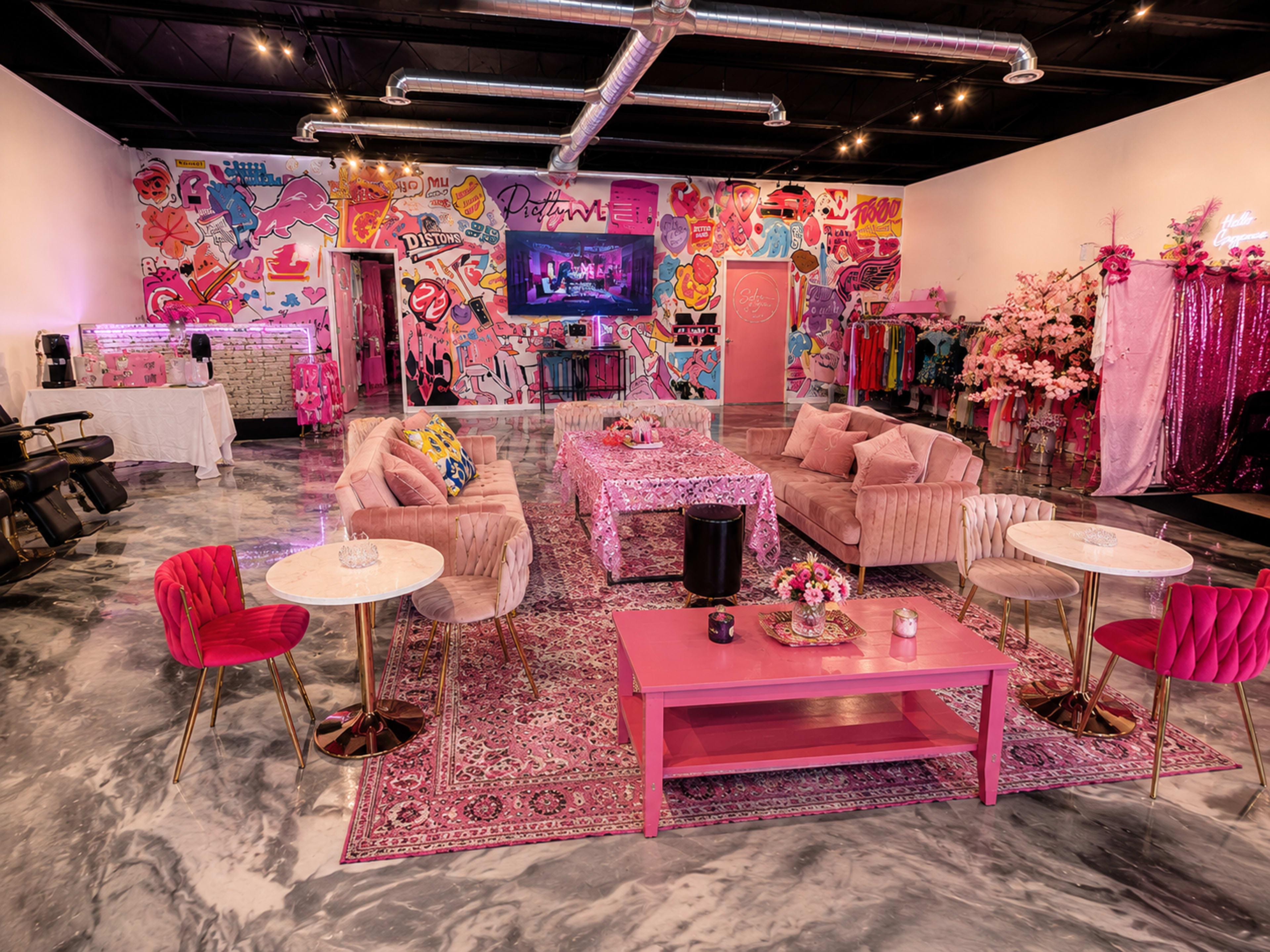 The image features a vibrant, colorful lounge space adorned with pink furniture, modern decor, and walls decorated with various pop art designs.