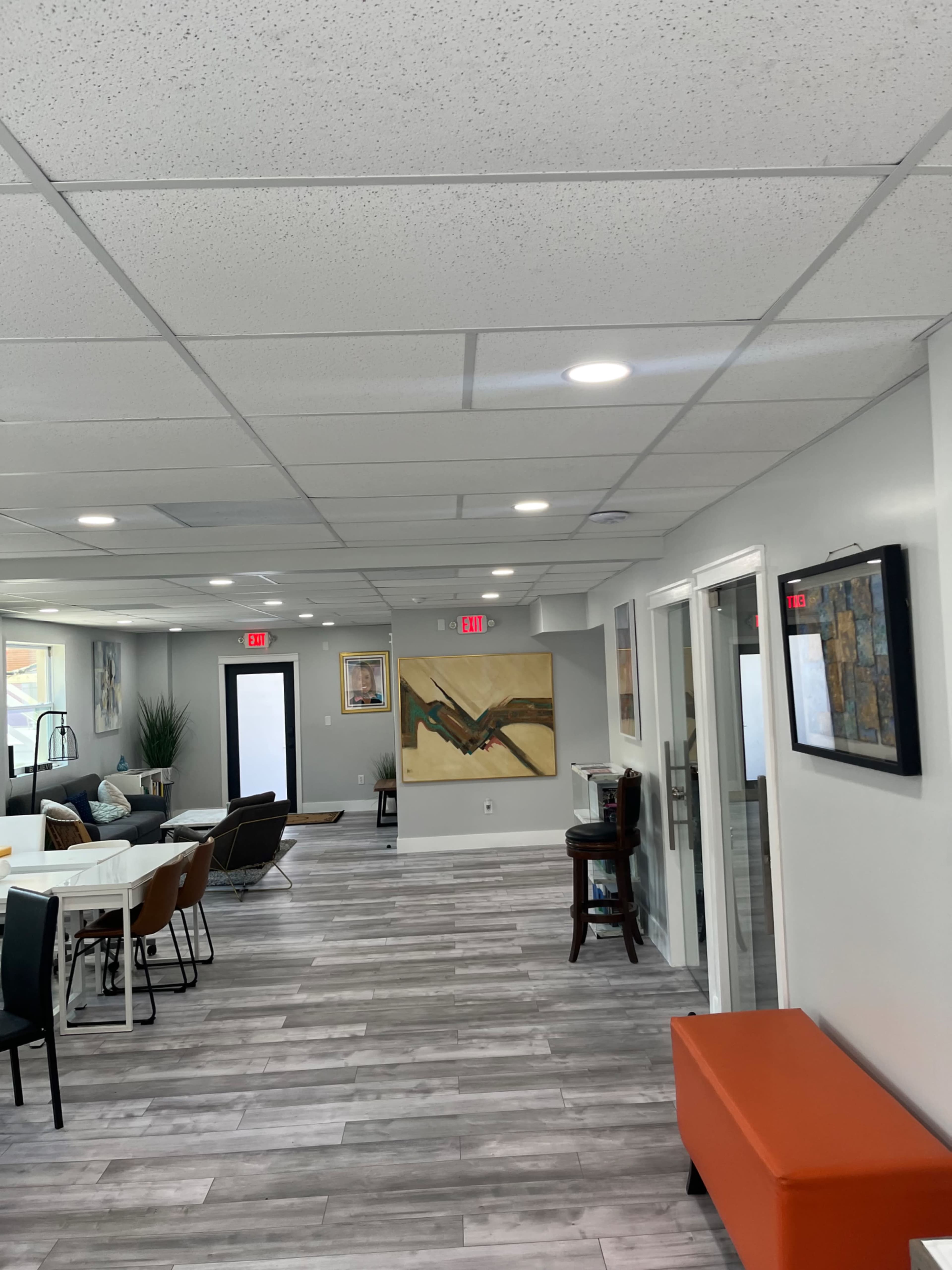 A modern interior space with a combination of seating areas, a dining table, and artwork on the walls.