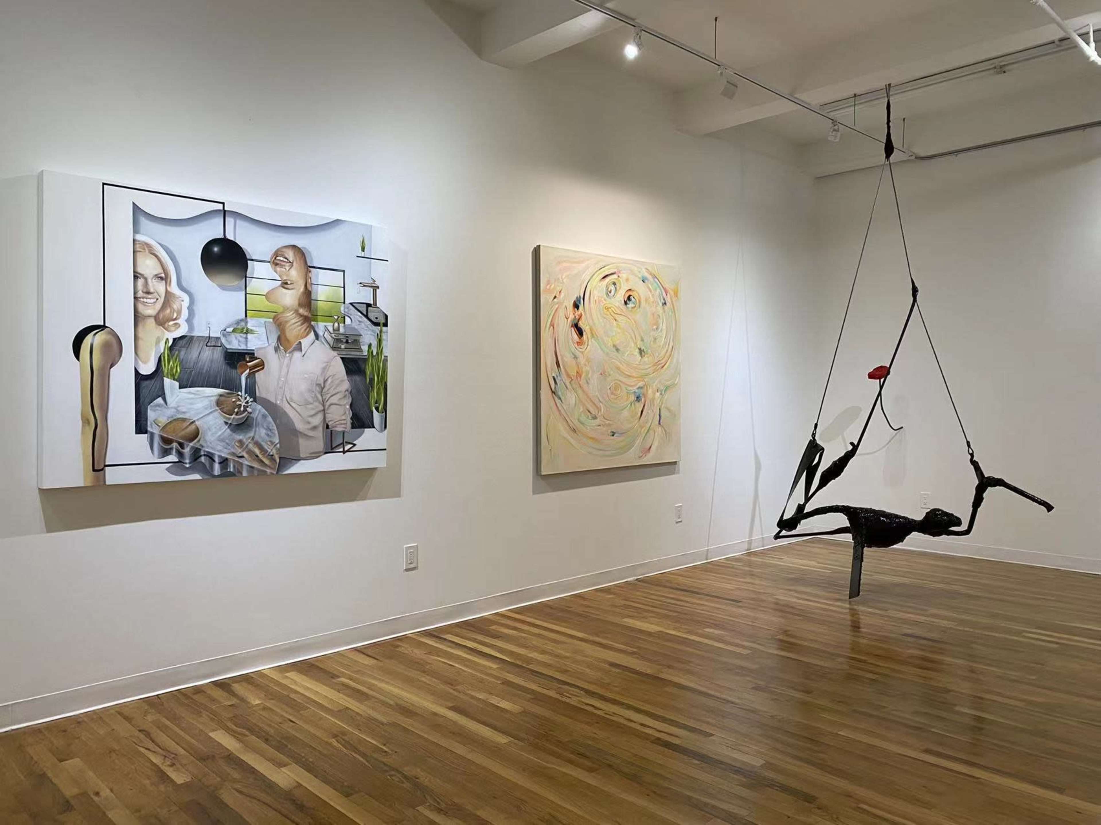 An art gallery featuring two paintings on the walls and a hanging sculpture in the center.