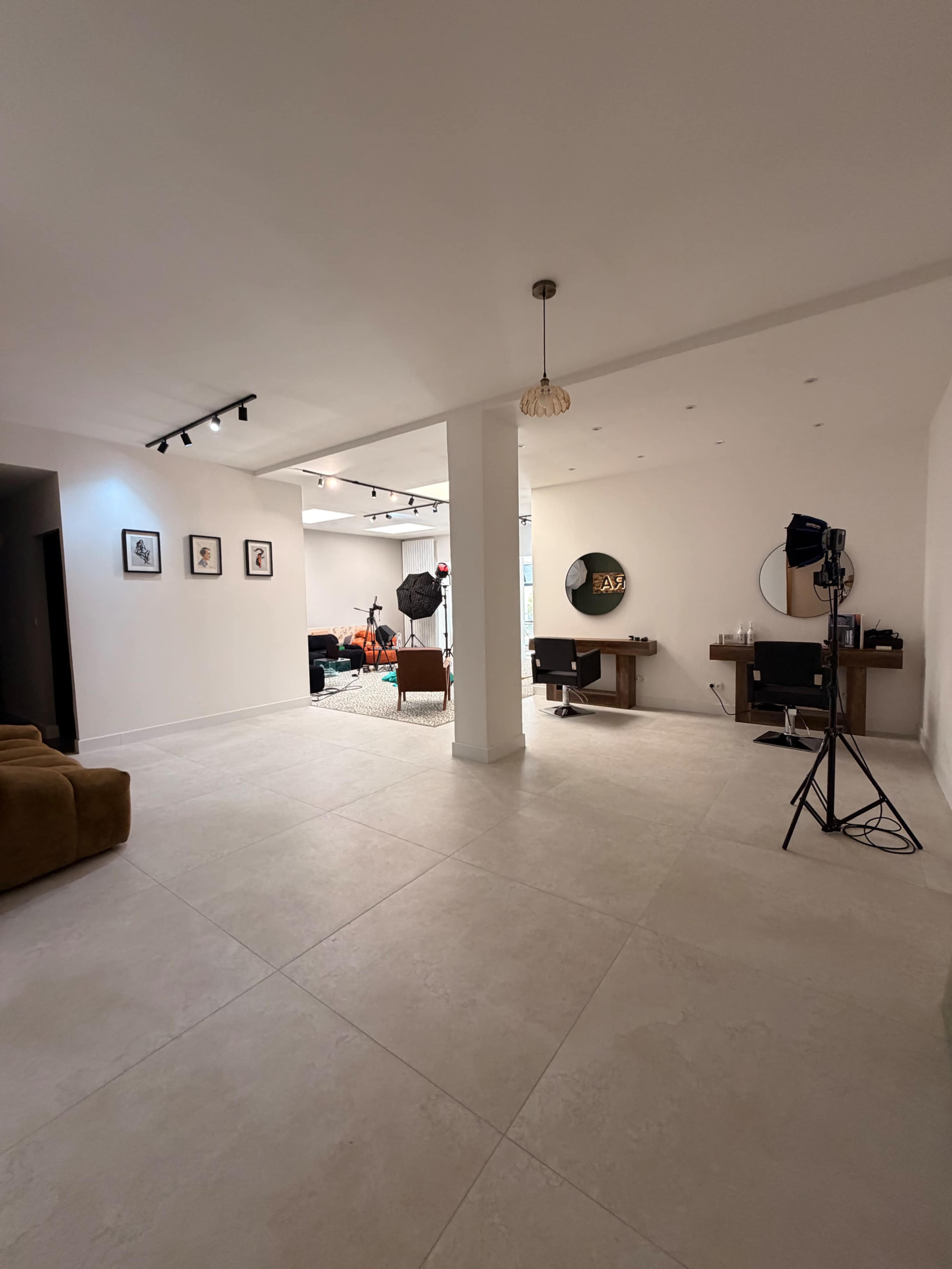 The image shows a spacious, modern room with a light-colored tiled floor, minimal furniture, and natural lighting.