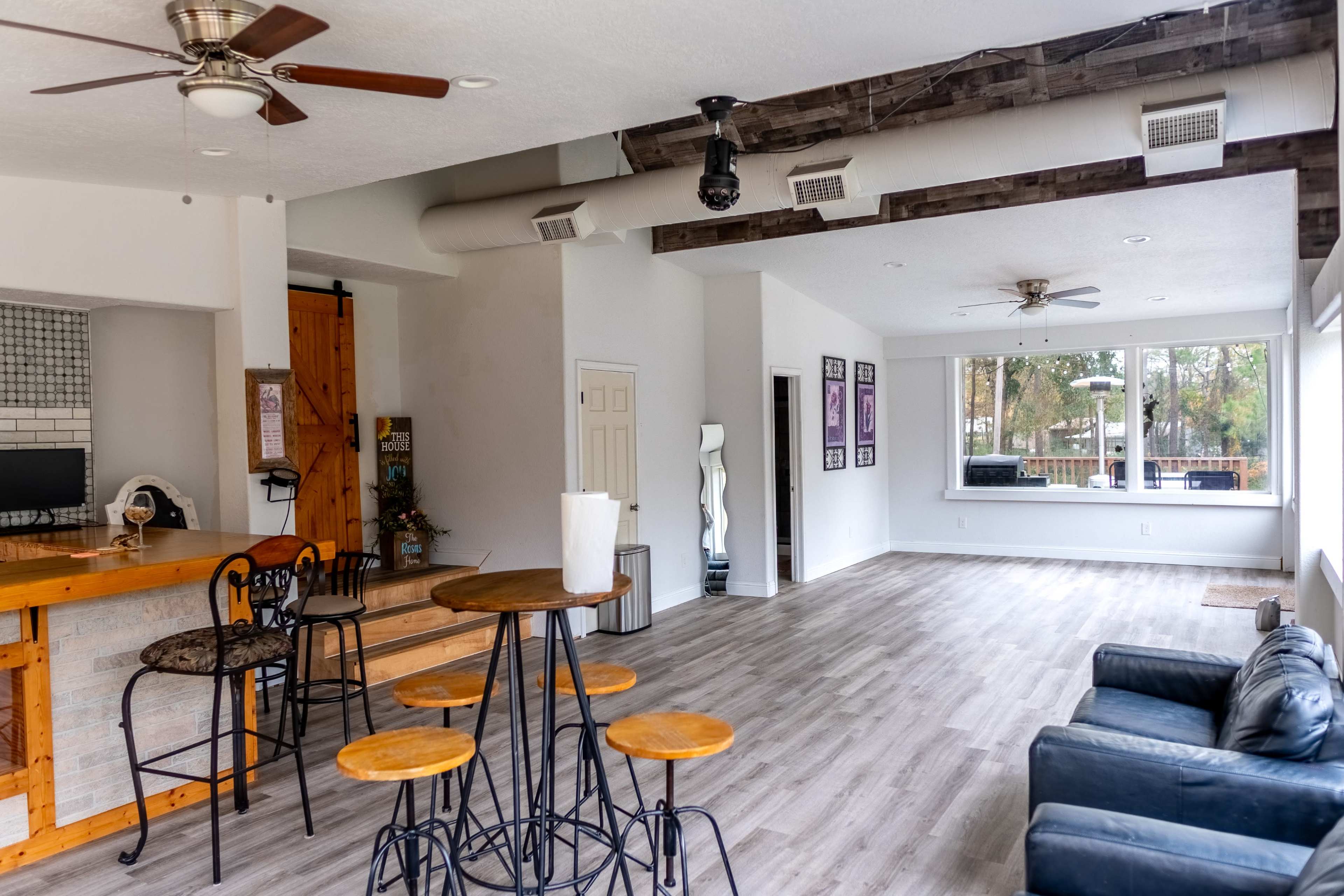 The image shows a spacious, modern interior with a bar area, a seating section, and large windows that allow natural light to enter.