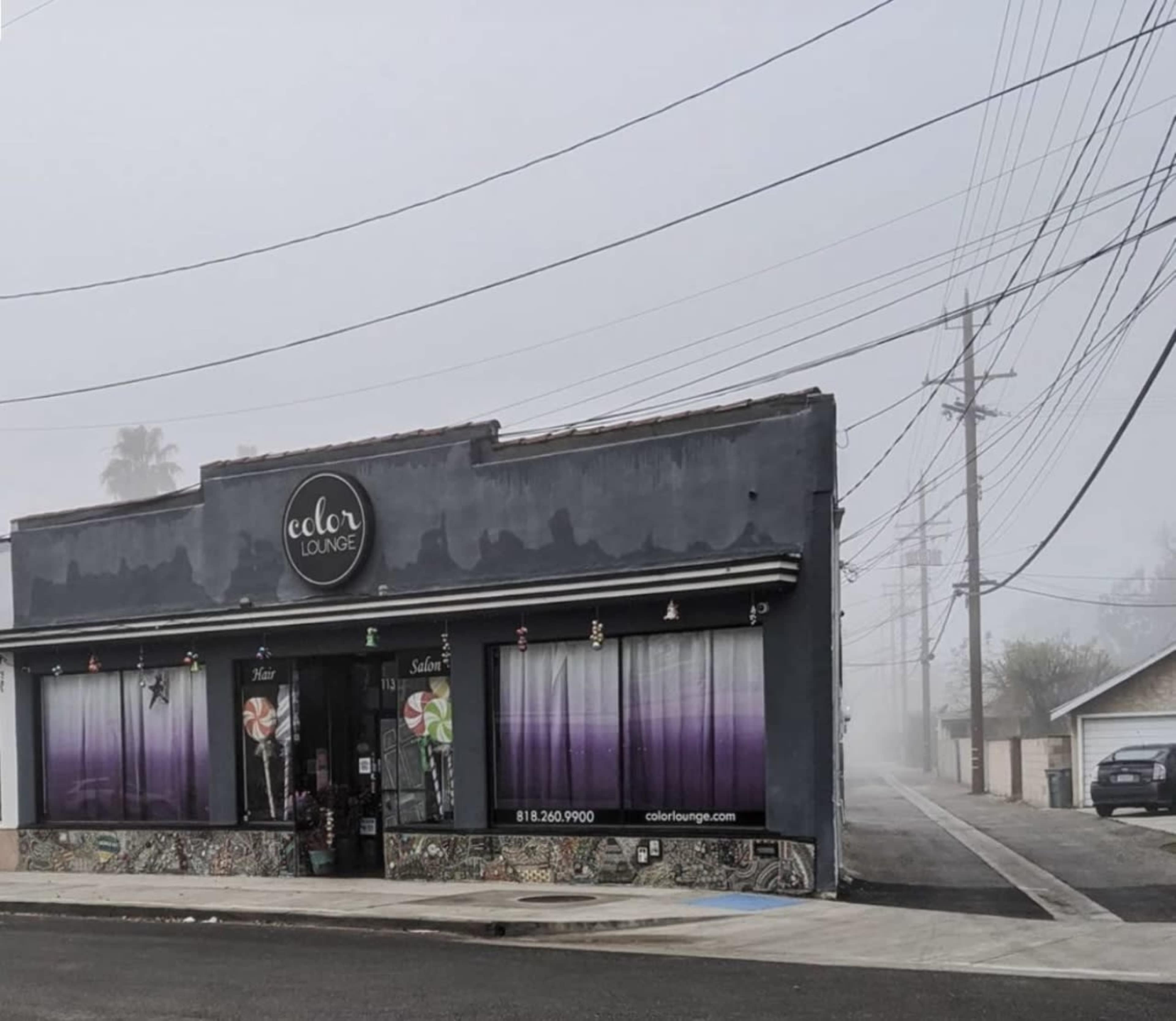 A foggy street scene features a hair salon called "Color Lounge" with large windows and an alley in the background.