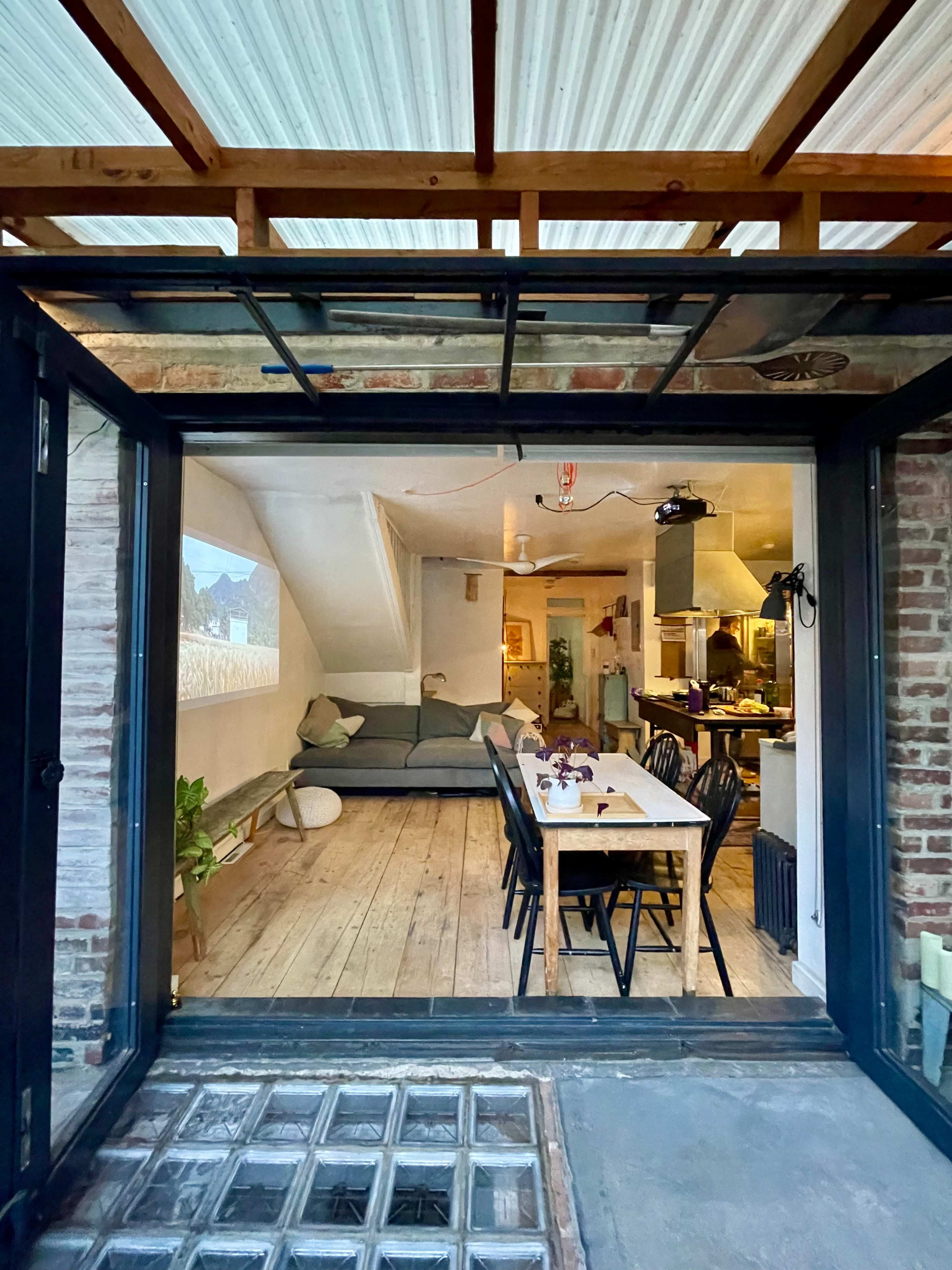 A spacious open-concept living area features a dining table and a seating area, with large glass doors leading to an outdoor space.