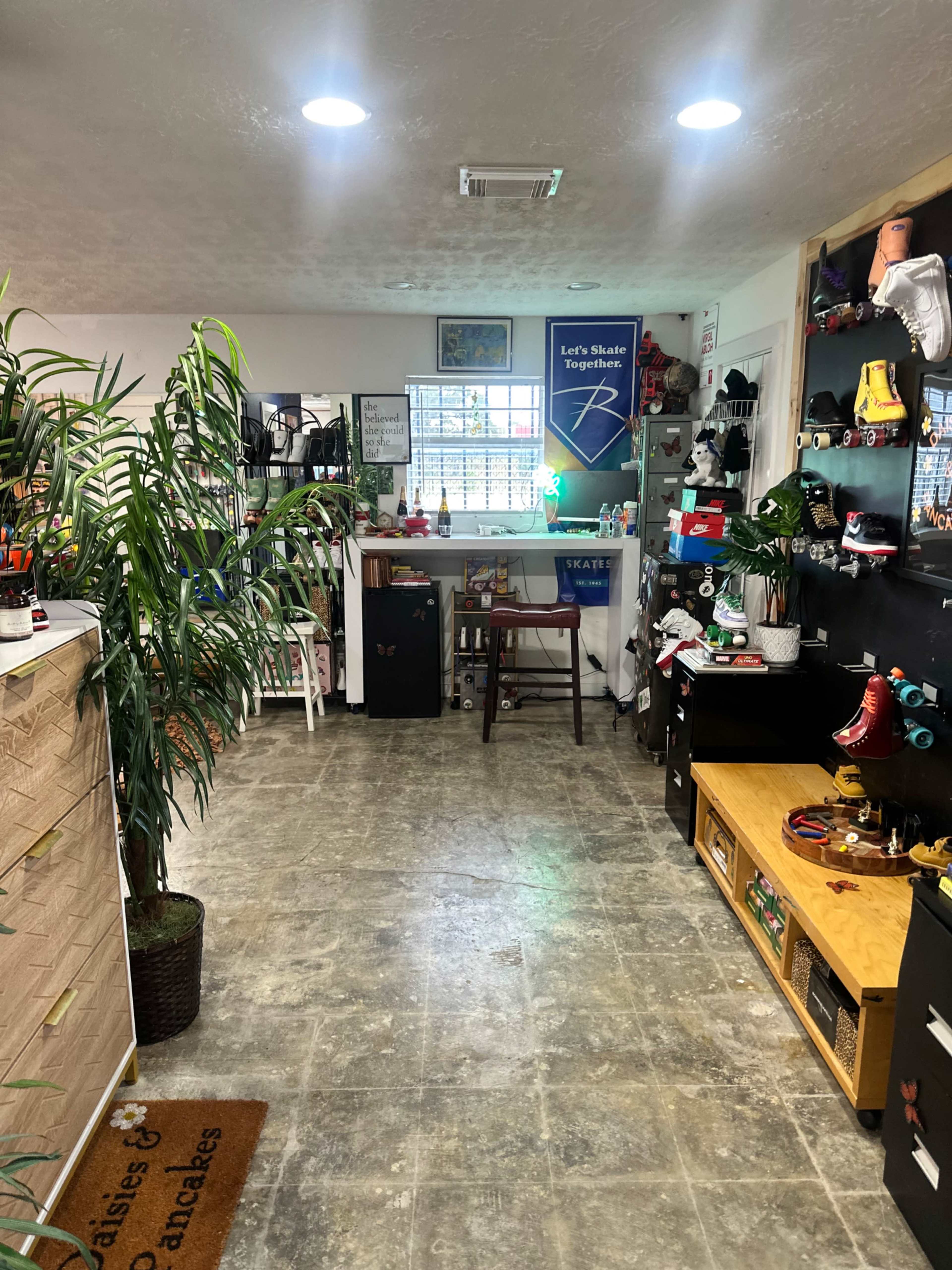The image shows an organized indoor space with a variety of roller skates, decorations, and plants, creating a lively atmosphere.