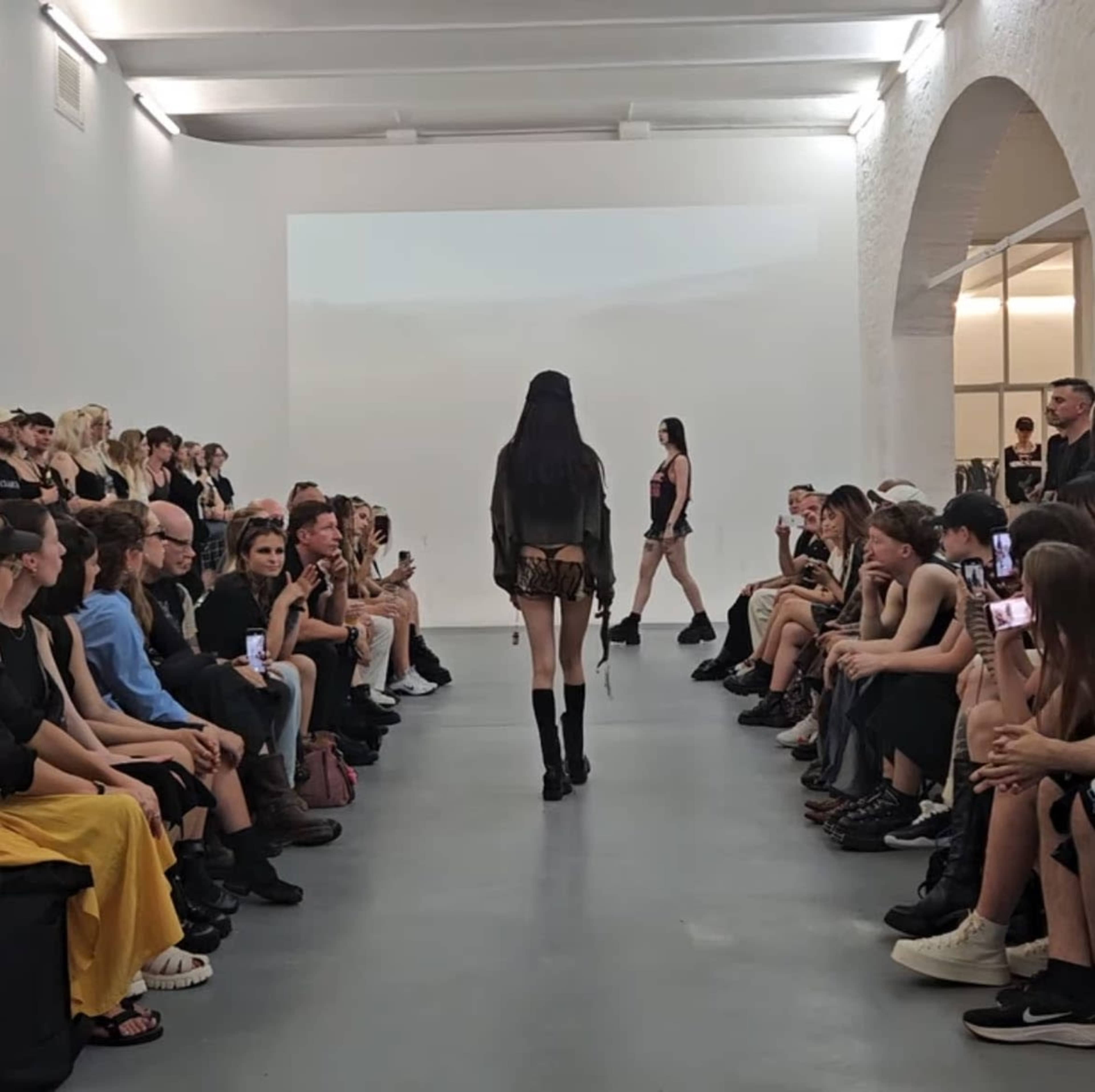 Models walk down a runway in front of an audience during a fashion show.
