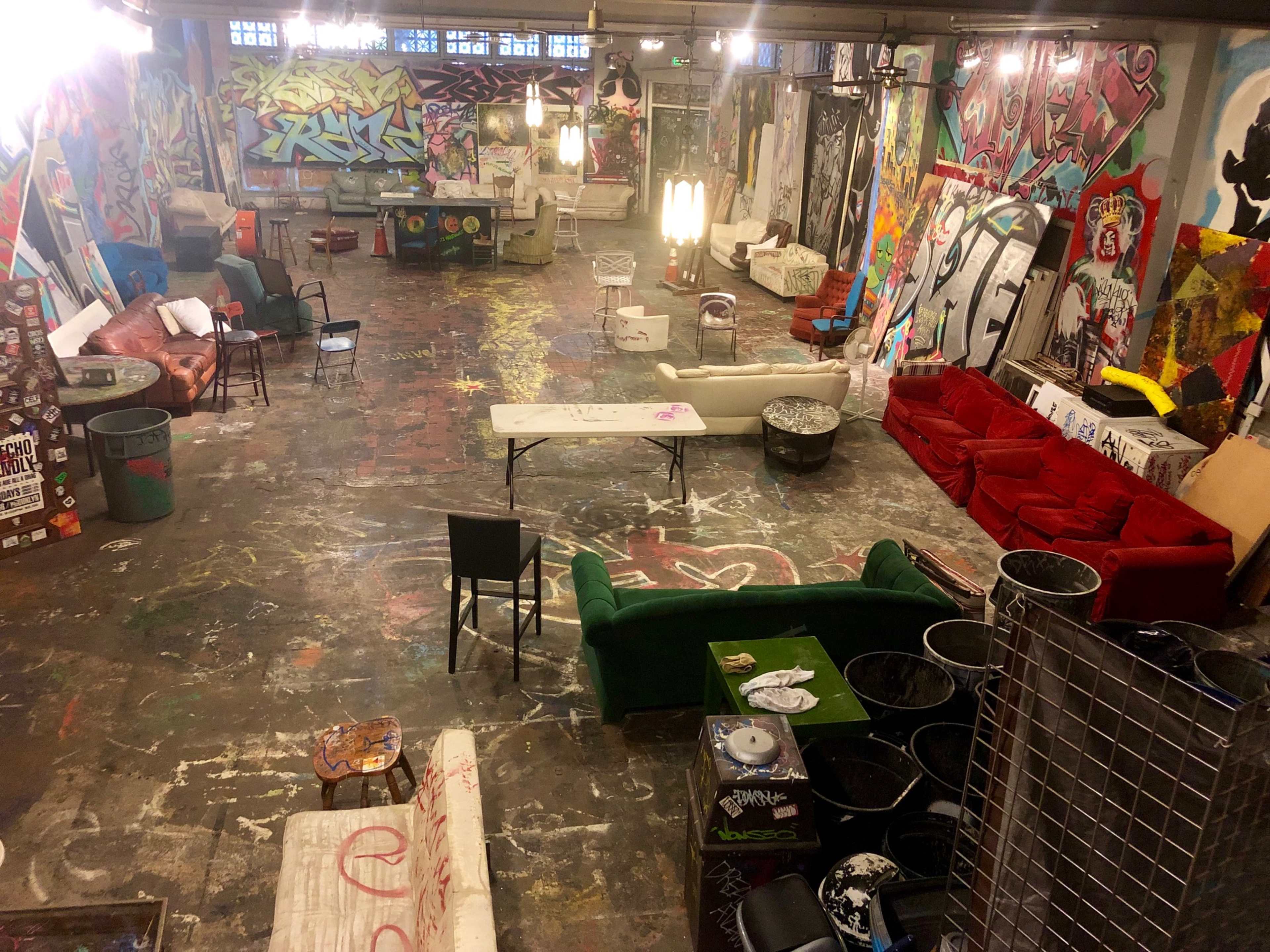 An interior space filled with various sofas and tables, surrounded by colorful graffiti on the walls.