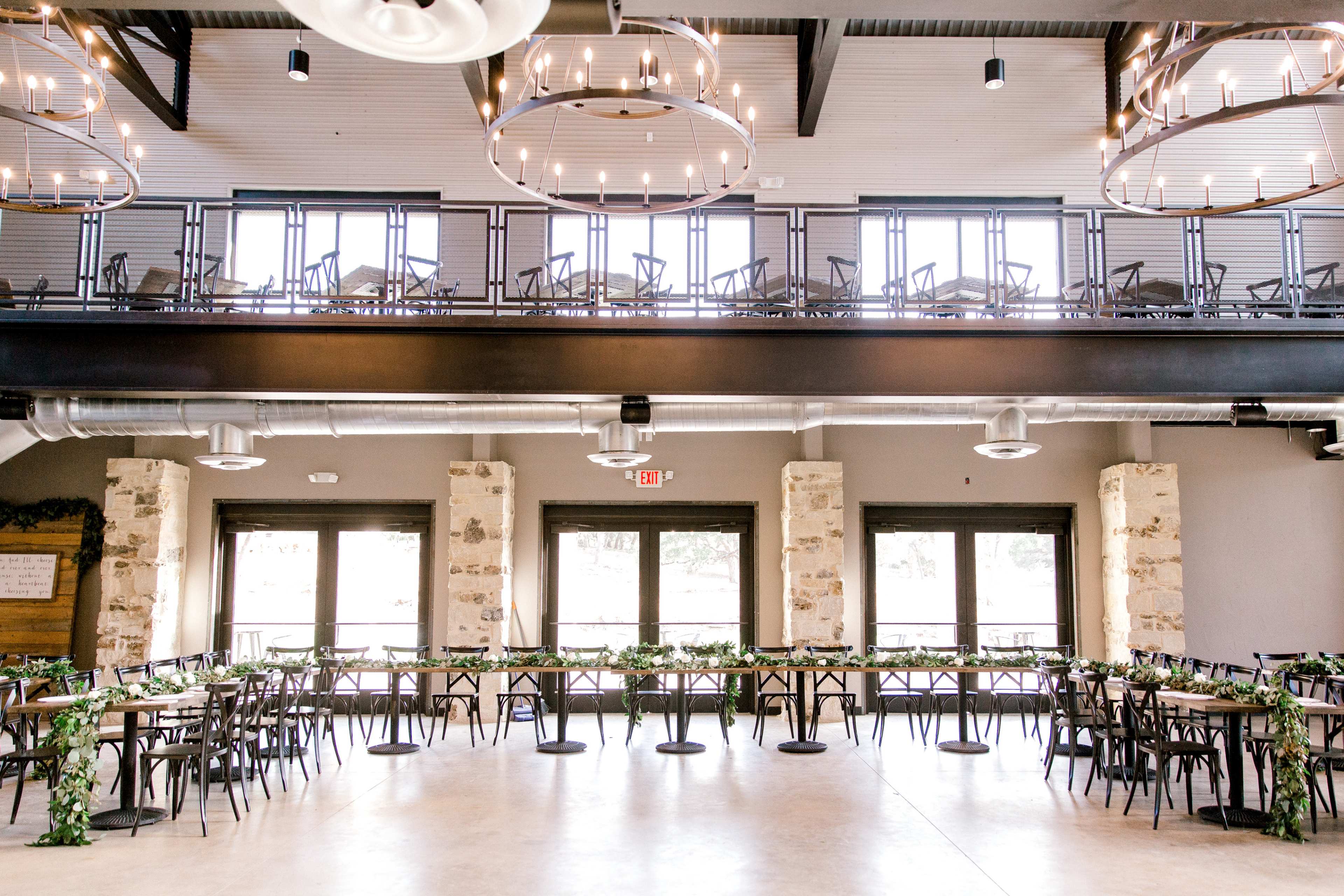 The image shows a dining area with rows of tables and chairs arranged neatly, featuring large windows and modern light fixtures.