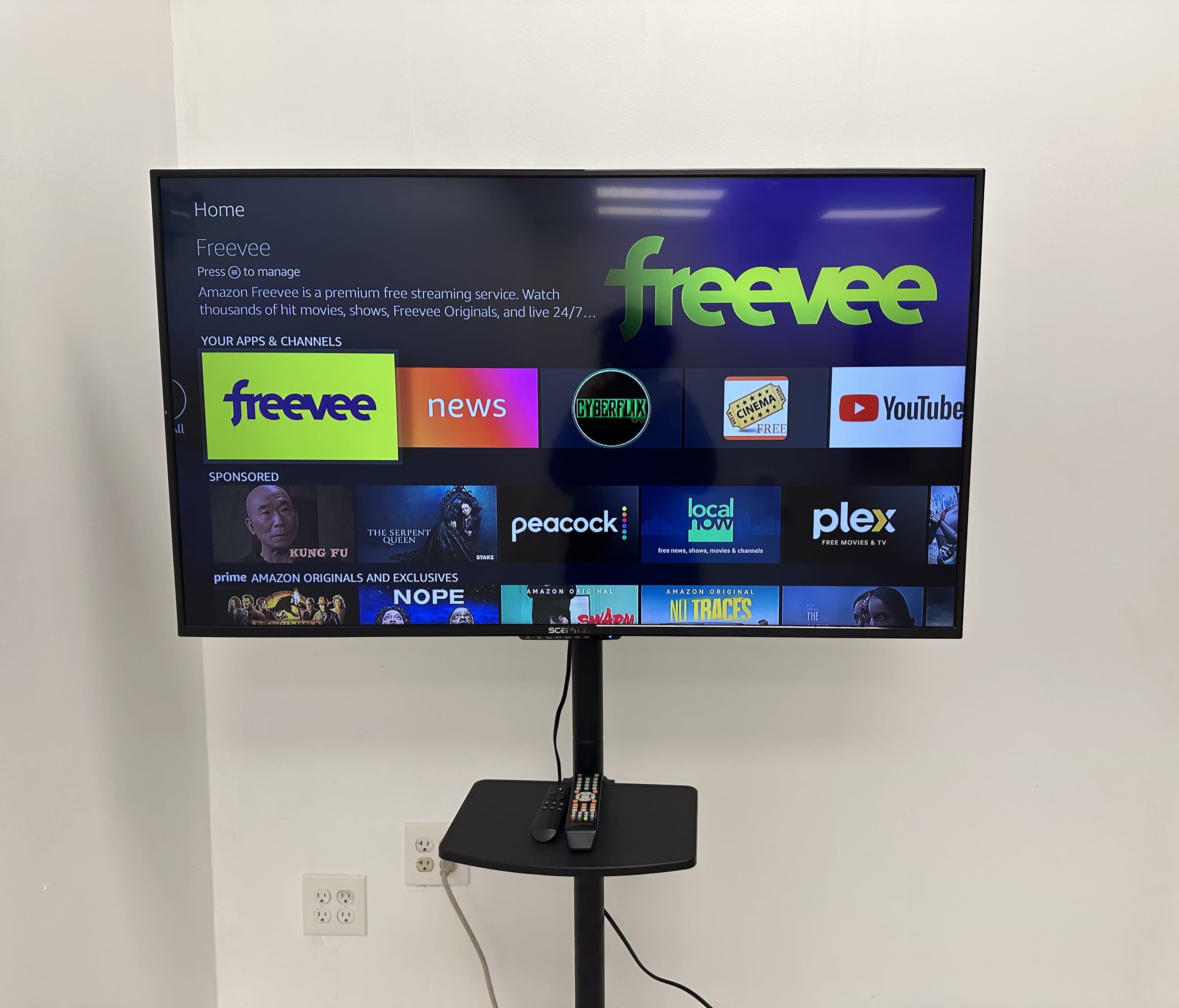 A flat-screen TV displays the home page of the Freevee streaming service, featuring various apps and channels available for selection.