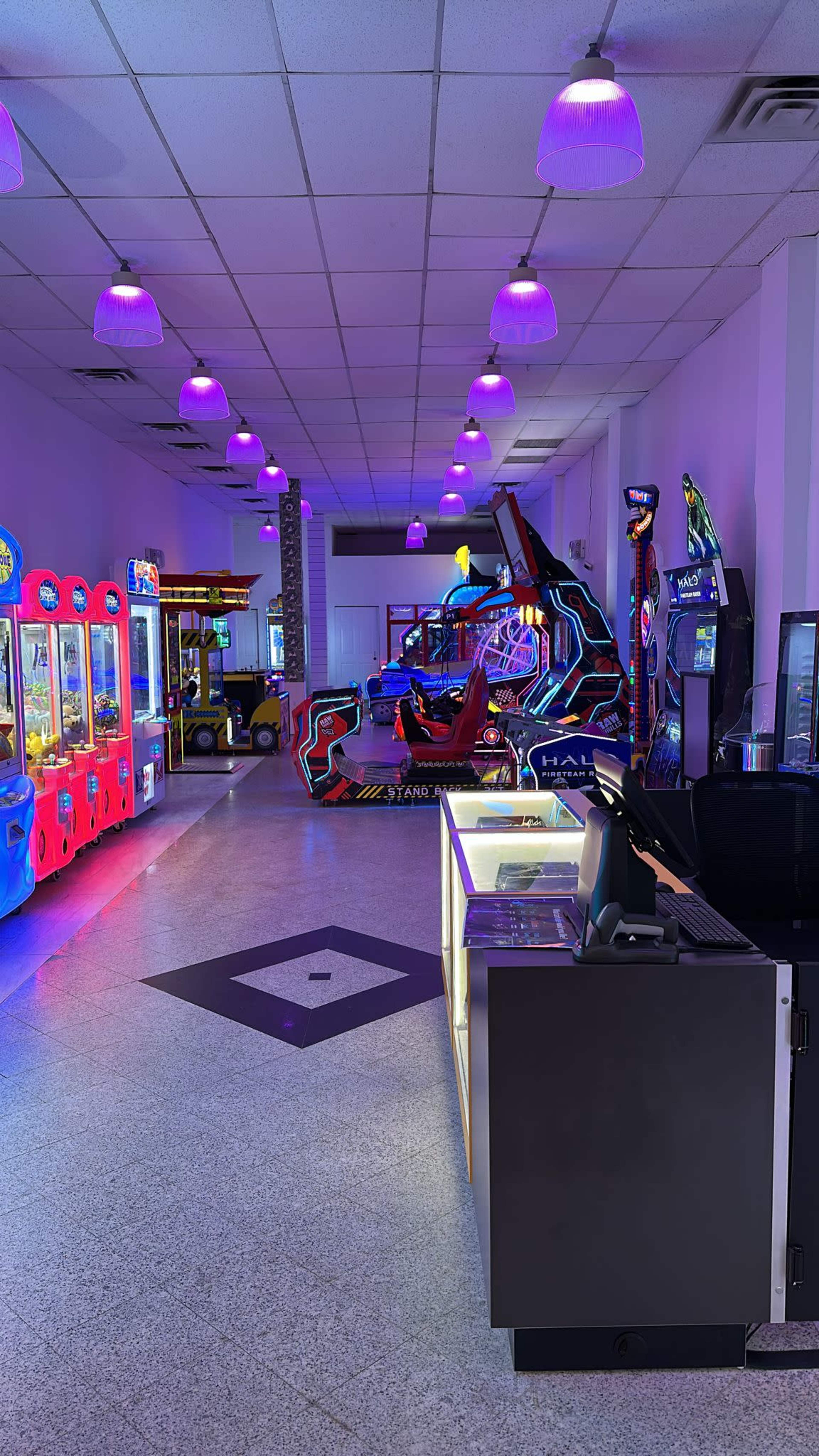 The image shows an arcade room with various colorful game machines and neon lighting.