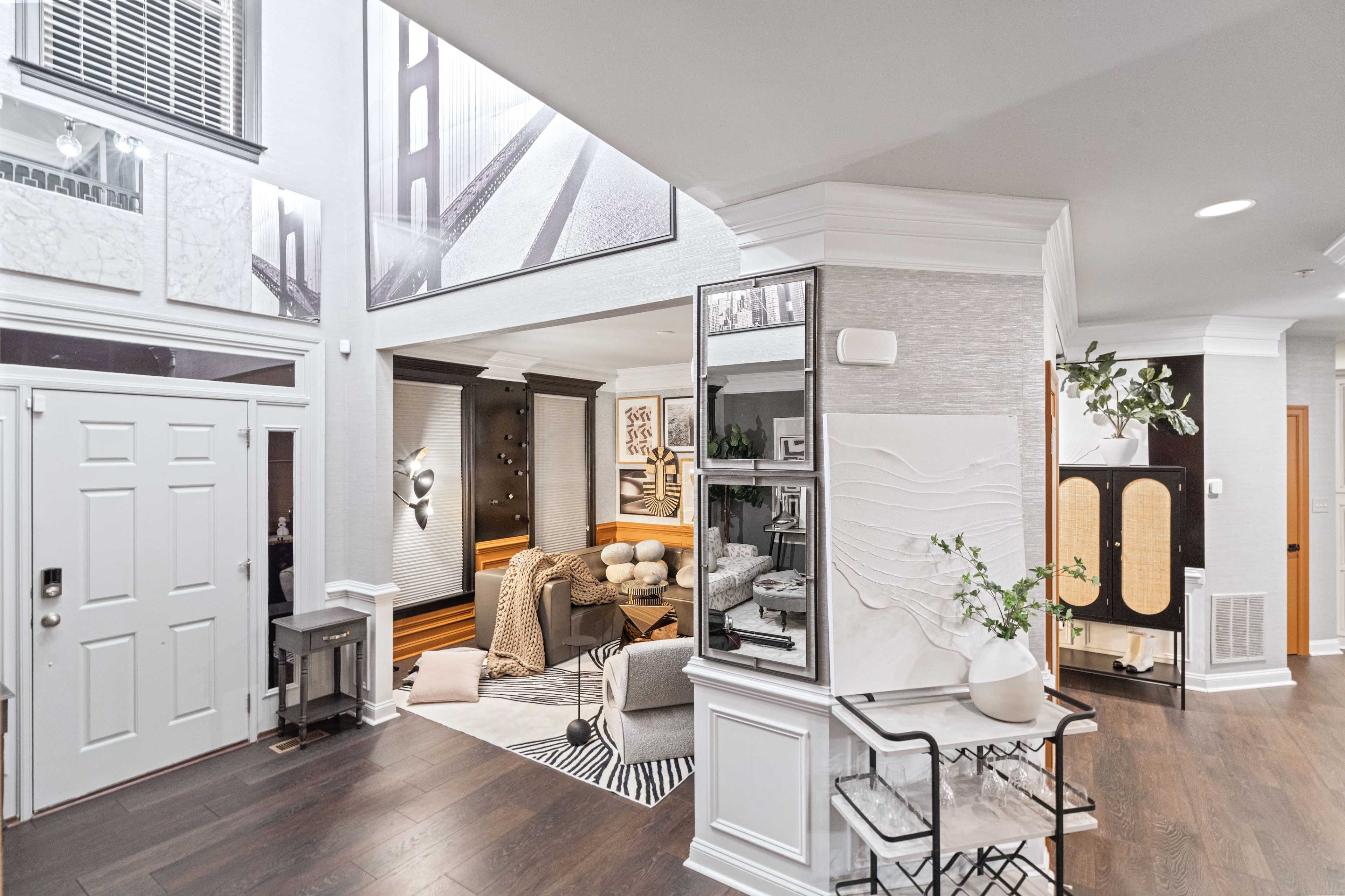 A modern, open-concept living space featuring a foyer with a decorative console table, a cozy seating area, and large wall art.
