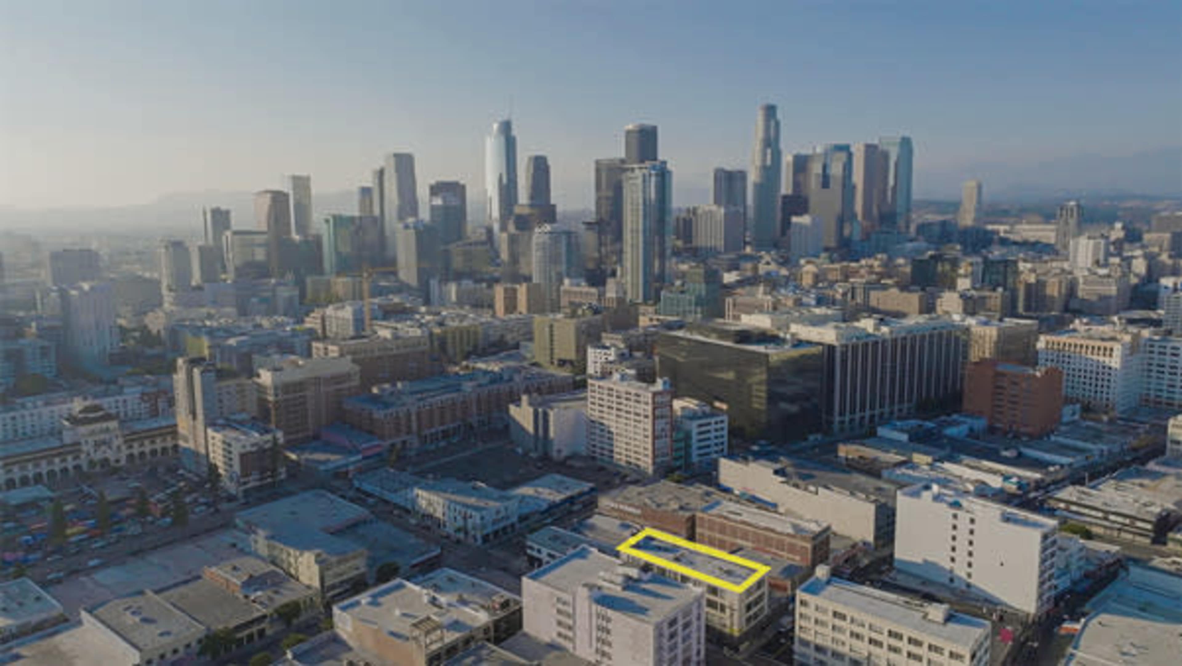 An aerial view of a city skyline featuring numerous skyscrapers with a yellow-highlighted building in the foreground.