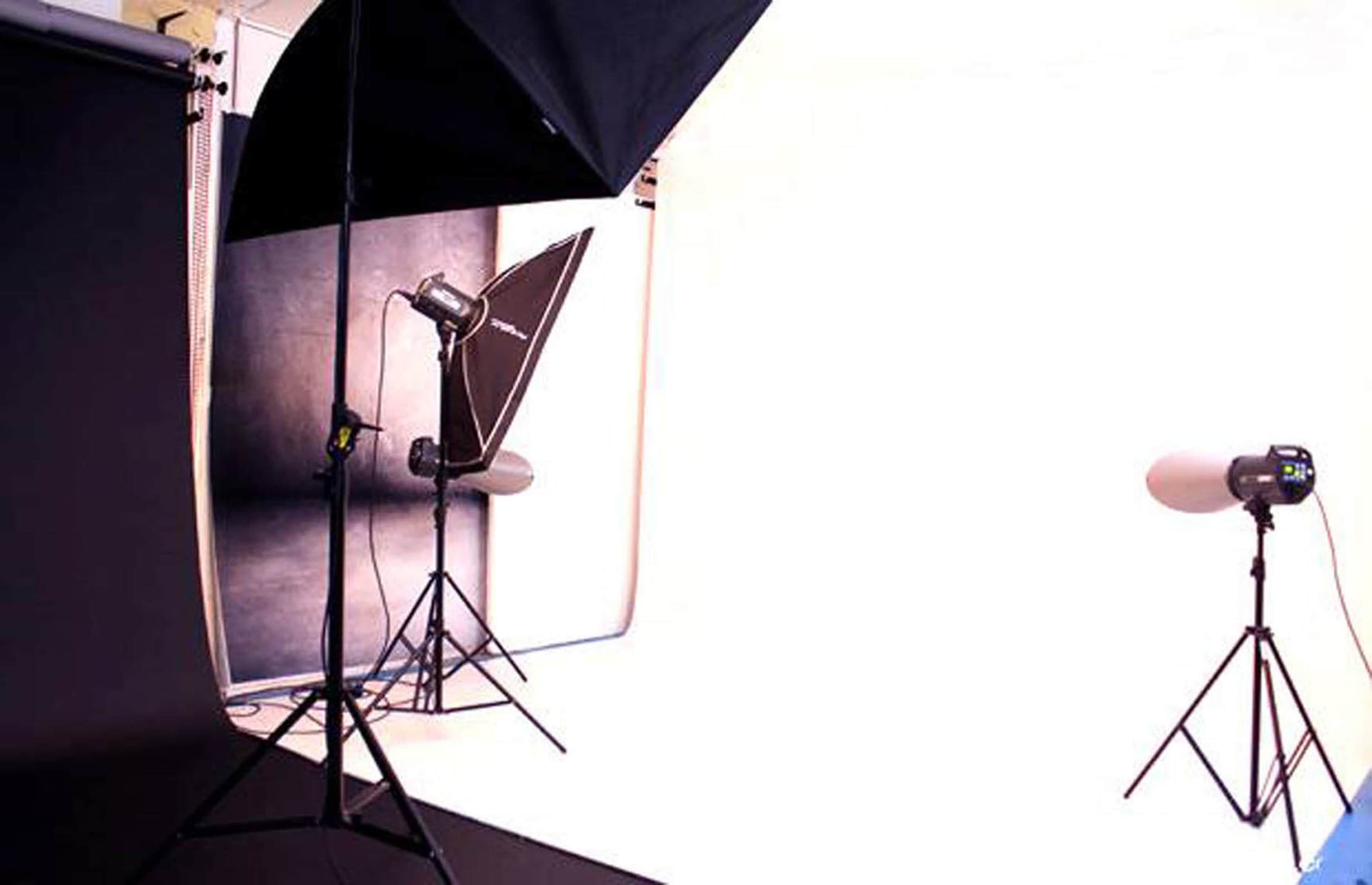 A photography studio setup with black and white backdrops and multiple lights positioned on tripods.