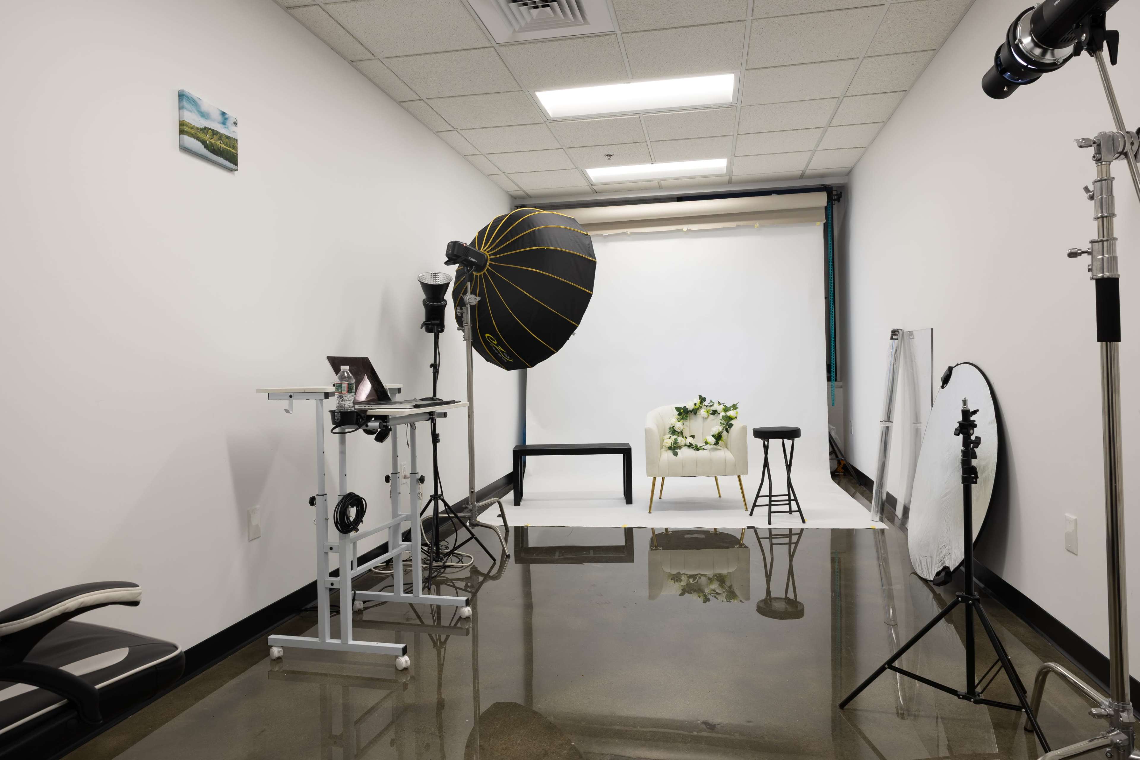 The image shows a photography studio equipped with a backdrop, lighting equipment, and seating arranged for a photo shoot.