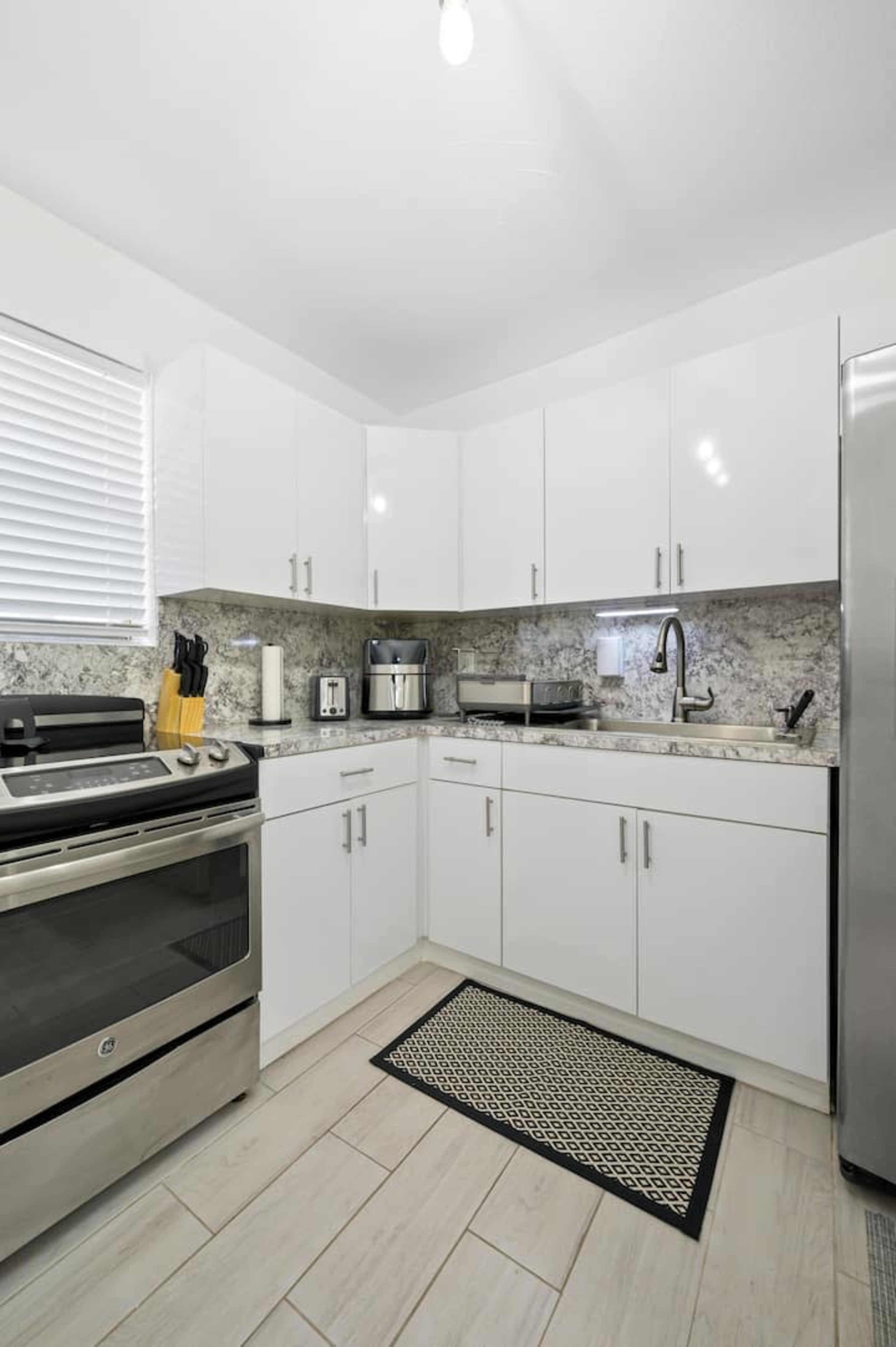 A modern kitchen features white cabinets, stainless steel appliances, and a gray granite countertop.