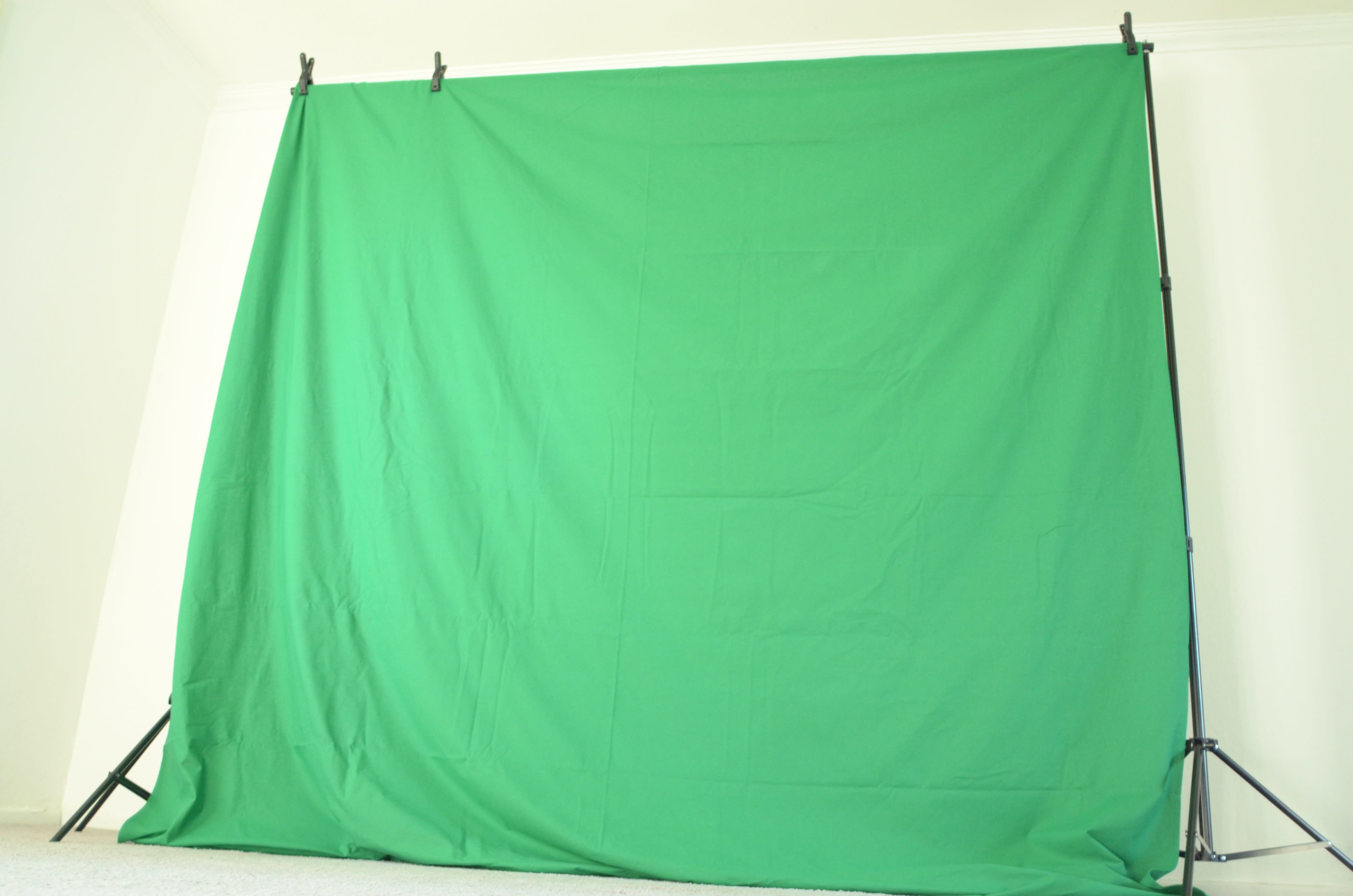 A green backdrop draped on a frame, typically used for video production or photography.