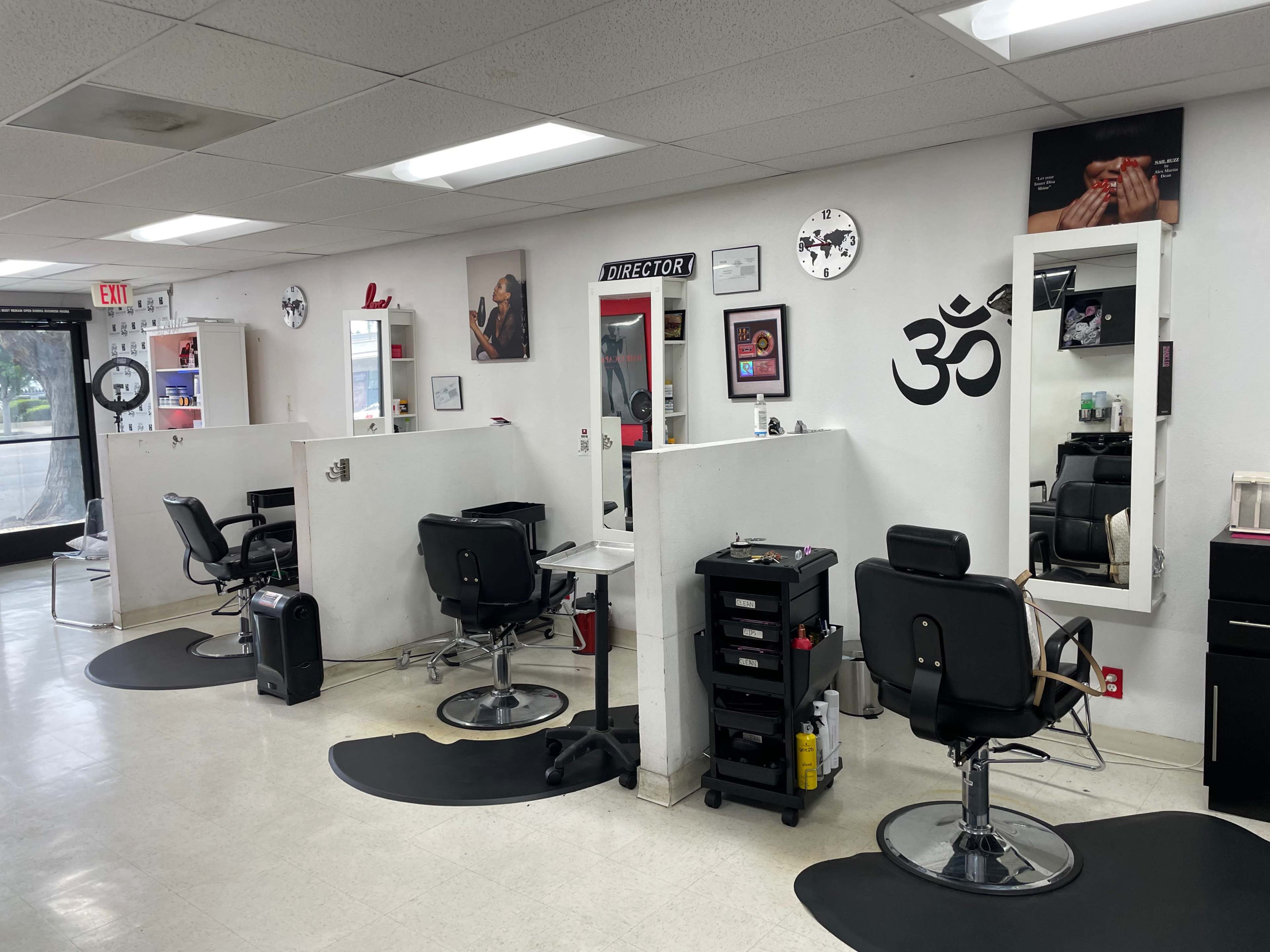 The interior of a barbershop with several styling stations, black salon chairs, mirrors, and a minimalist décor.