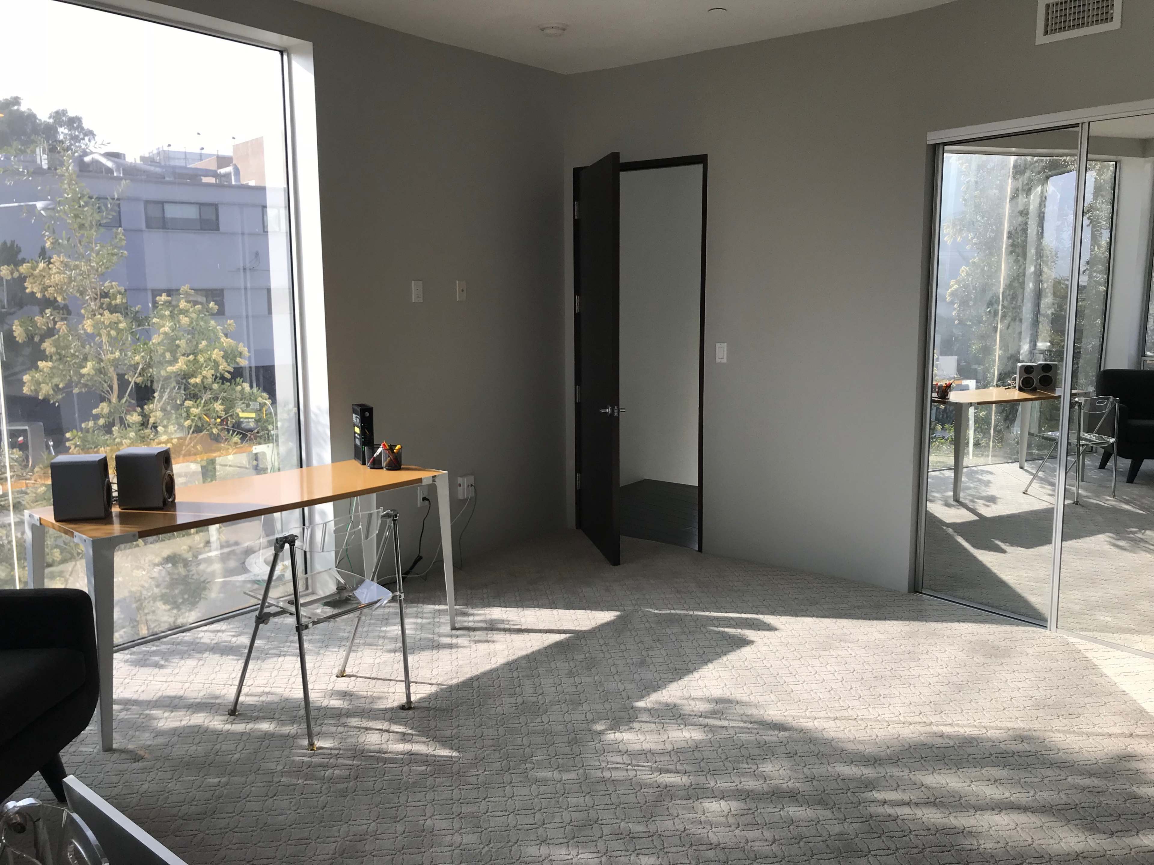 A modern, minimalist office space with a desk and an open door leading to another room.