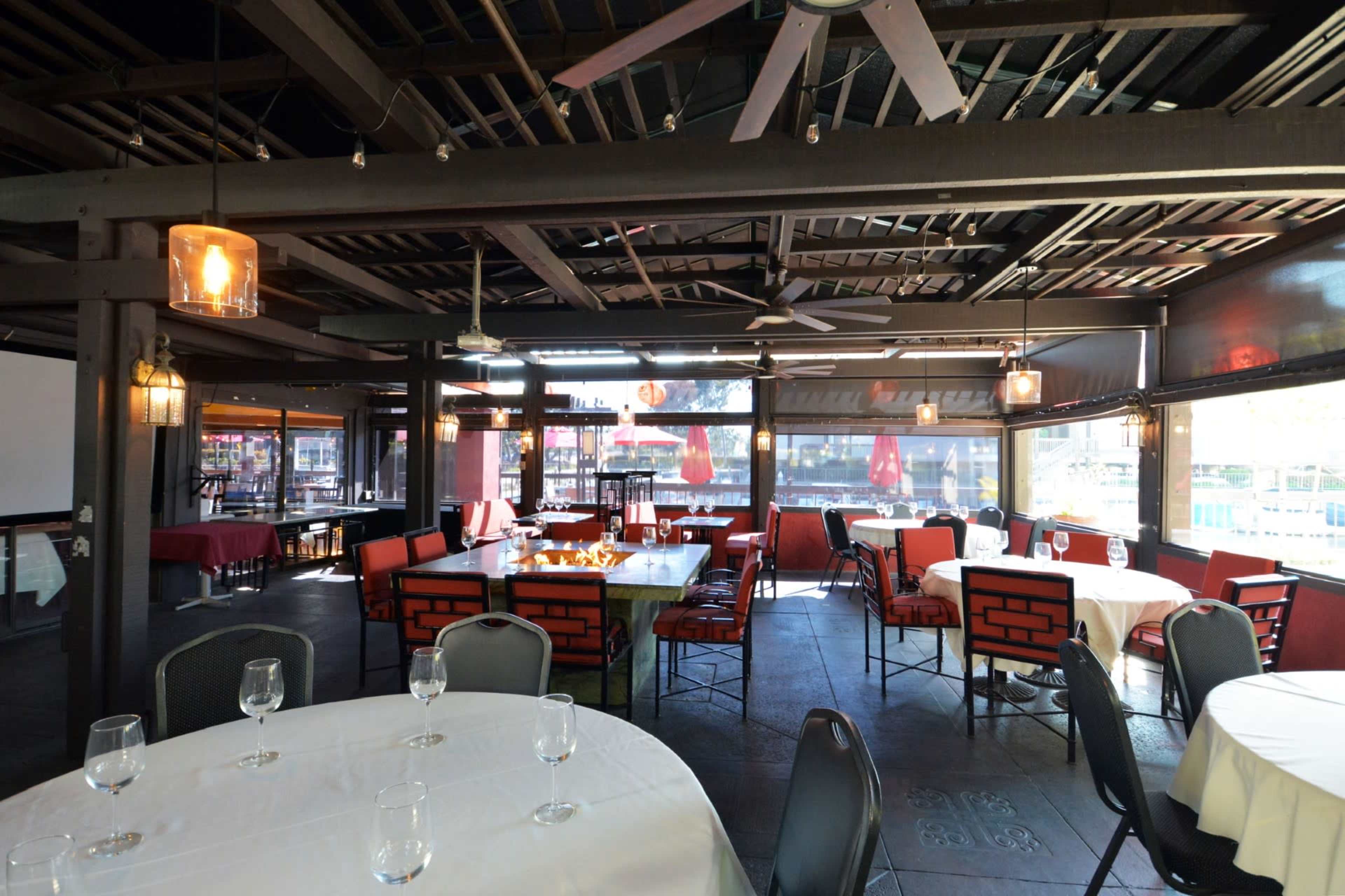 A spacious dining area with tables set for guests, featuring large windows and decorative light fixtures.