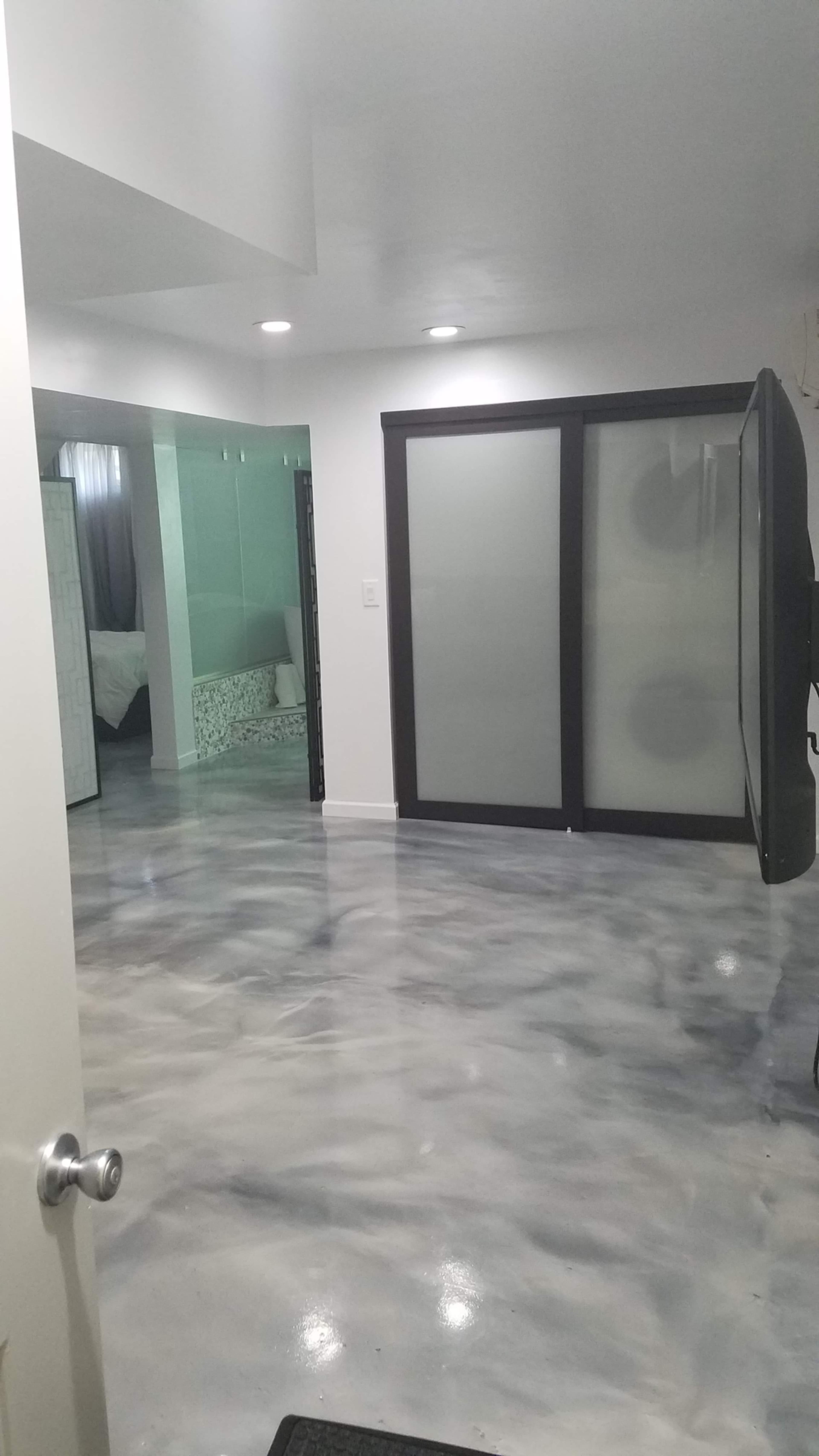 A modern room with a polished, patterned floor and sliding glass doors leading to another area.