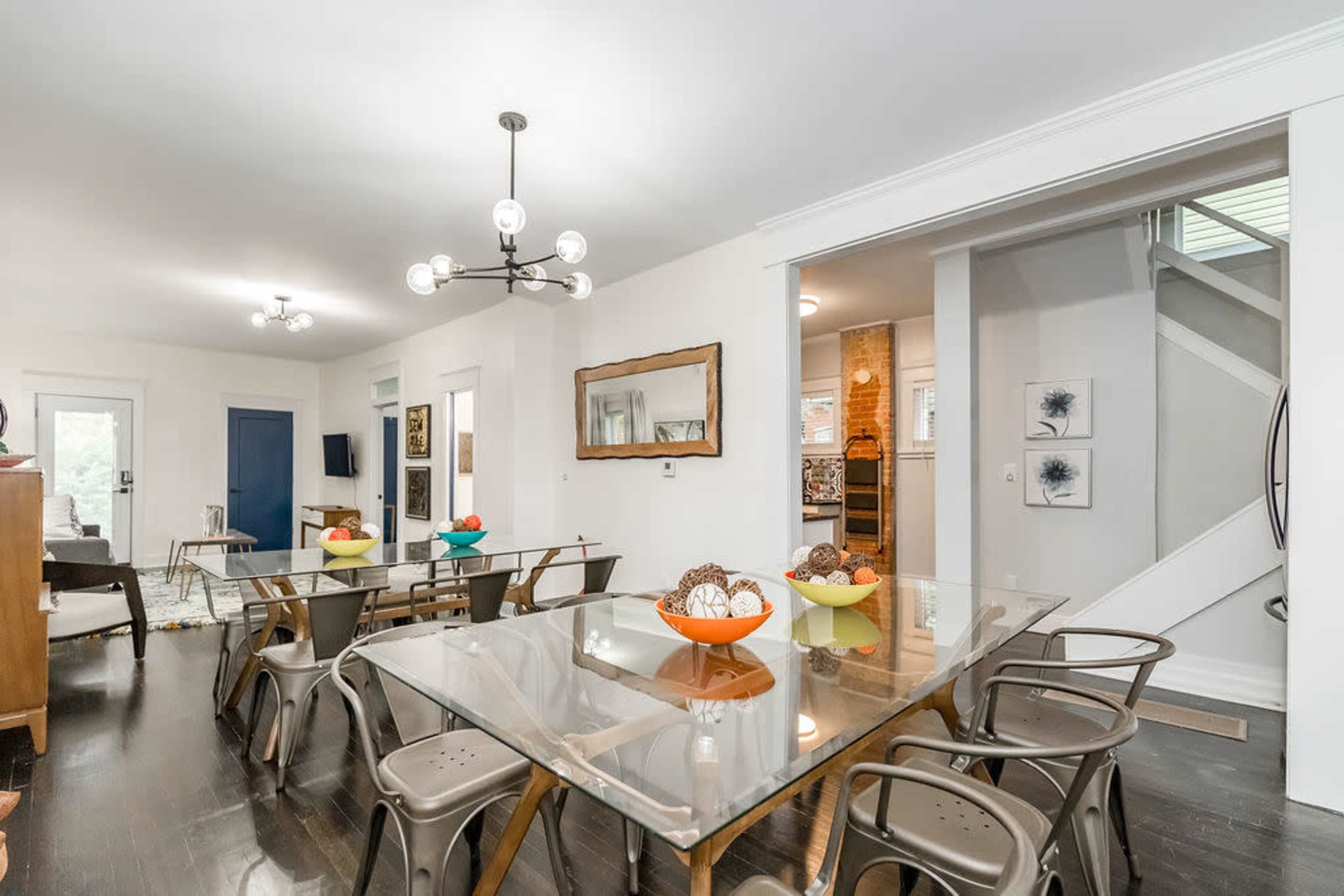 A dining area features multiple glass tables surrounded by metal chairs, with colorful bowls of decor in the center.
