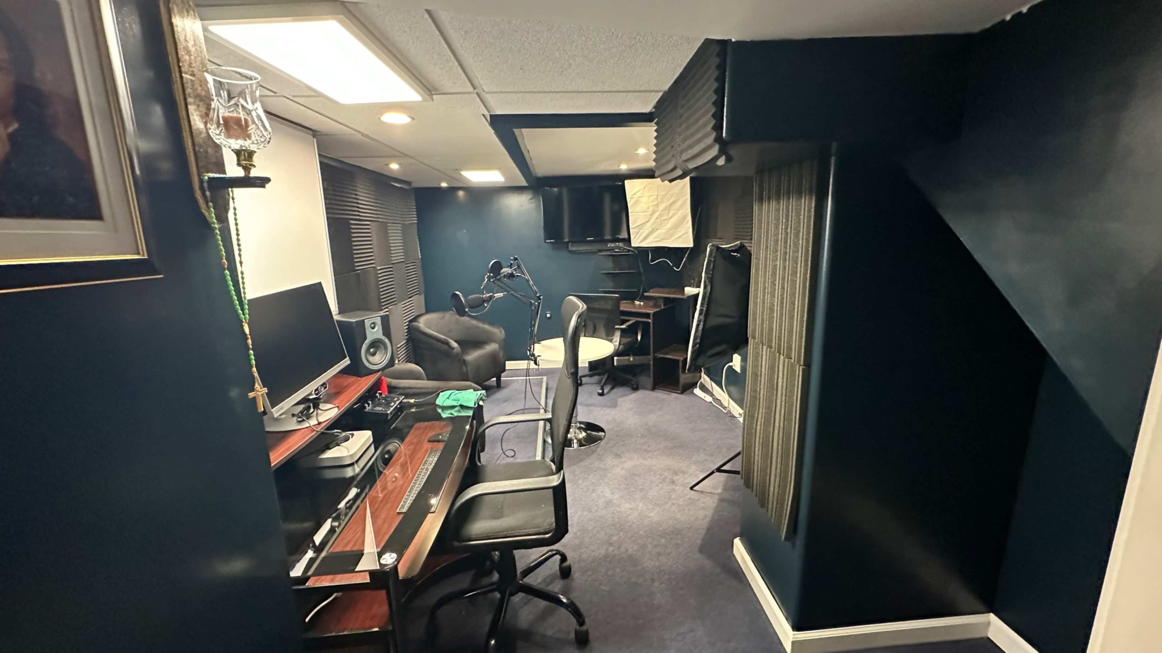 A modern home office with a desk, chair, computer setup, and soundproofing panels on the walls.