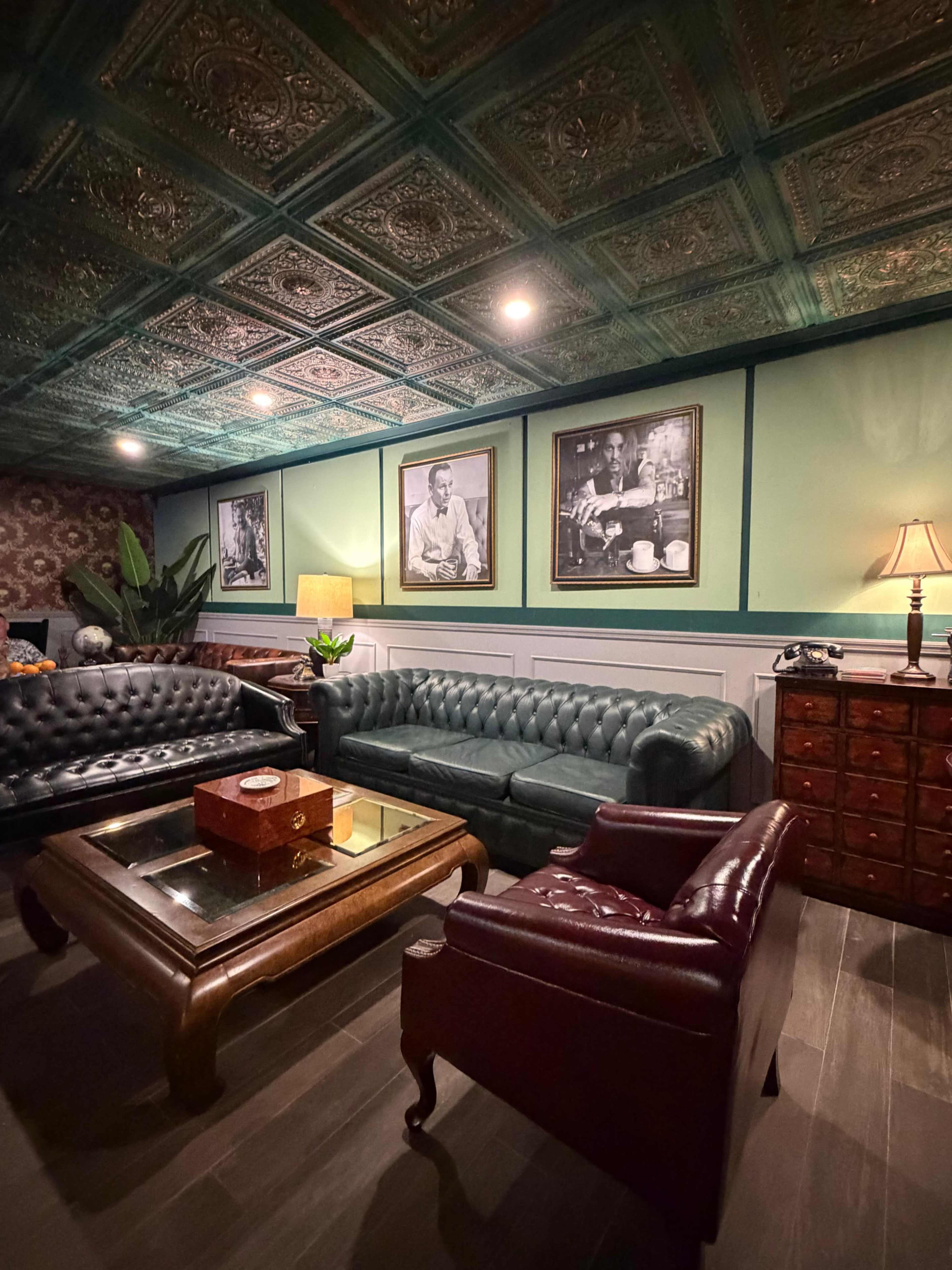 The scene features a cozy lounge with leather sofas, vintage photographs on the walls, and warm lighting from a lamp and overhead fixtures.