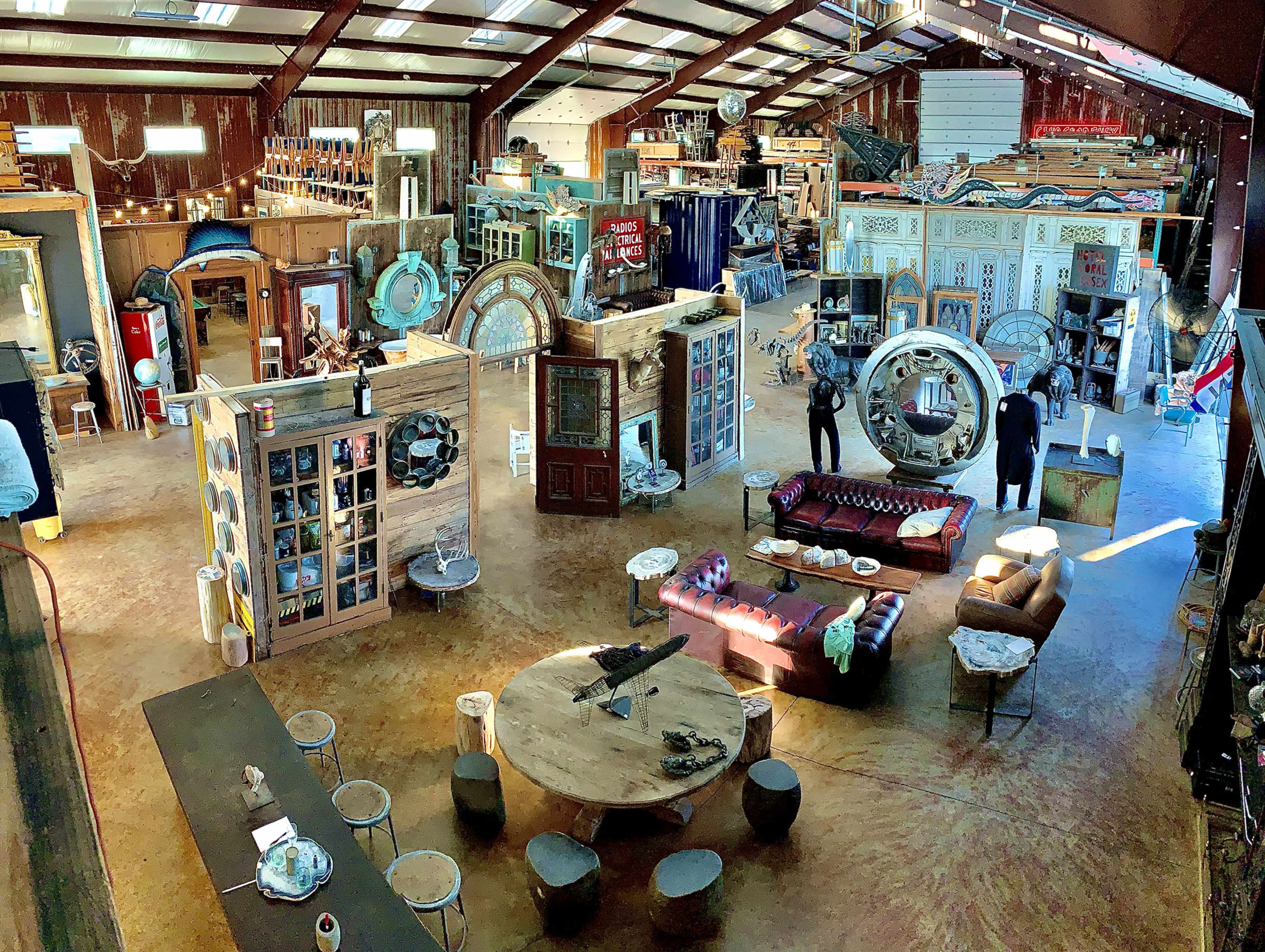 A large, open interior space filled with eclectic furniture, decorative items, and various display pieces arranged throughout the room.