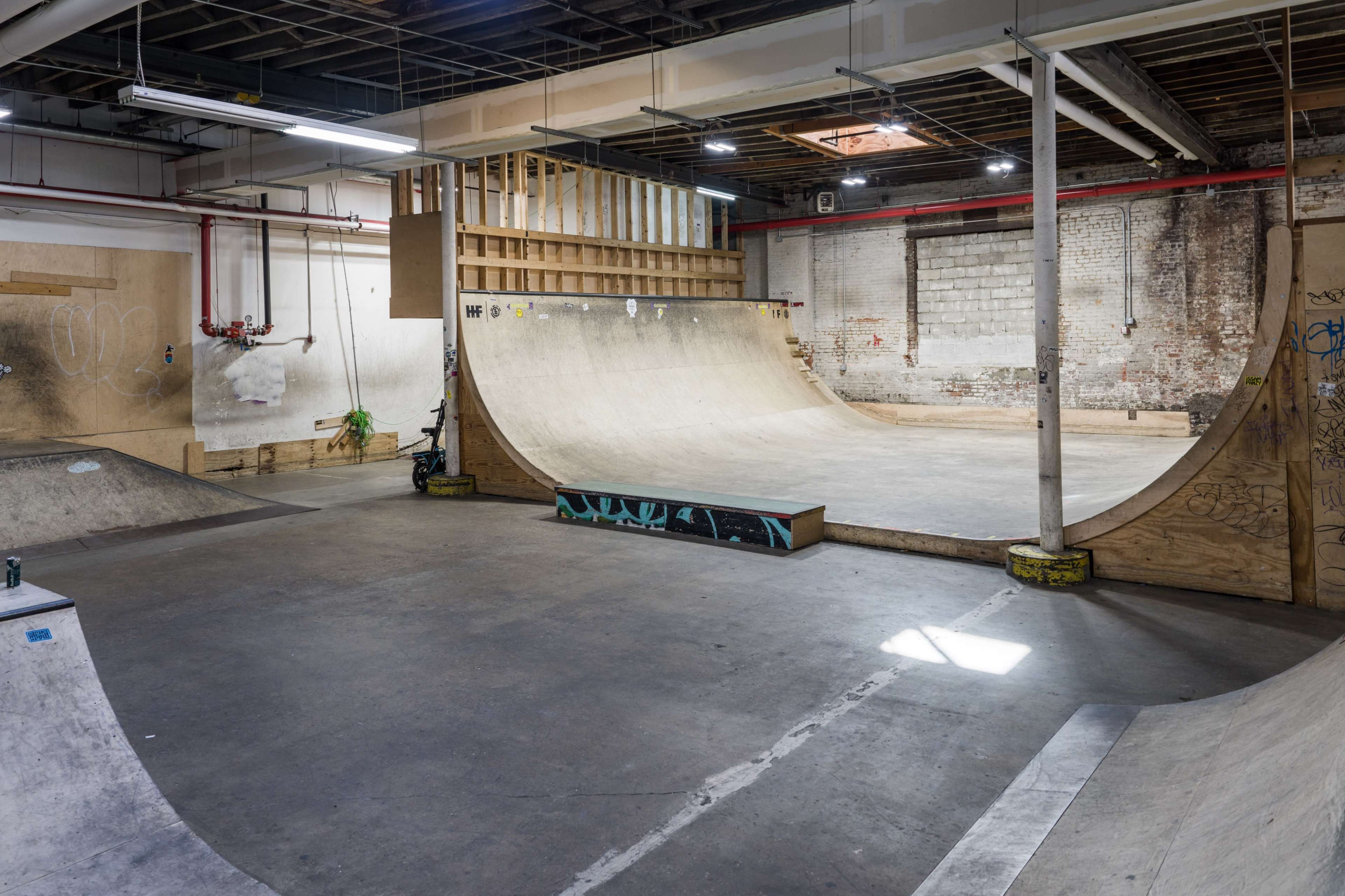 An indoor skatepark featuring various wooden ramps and a large, curved half-pipe structure.