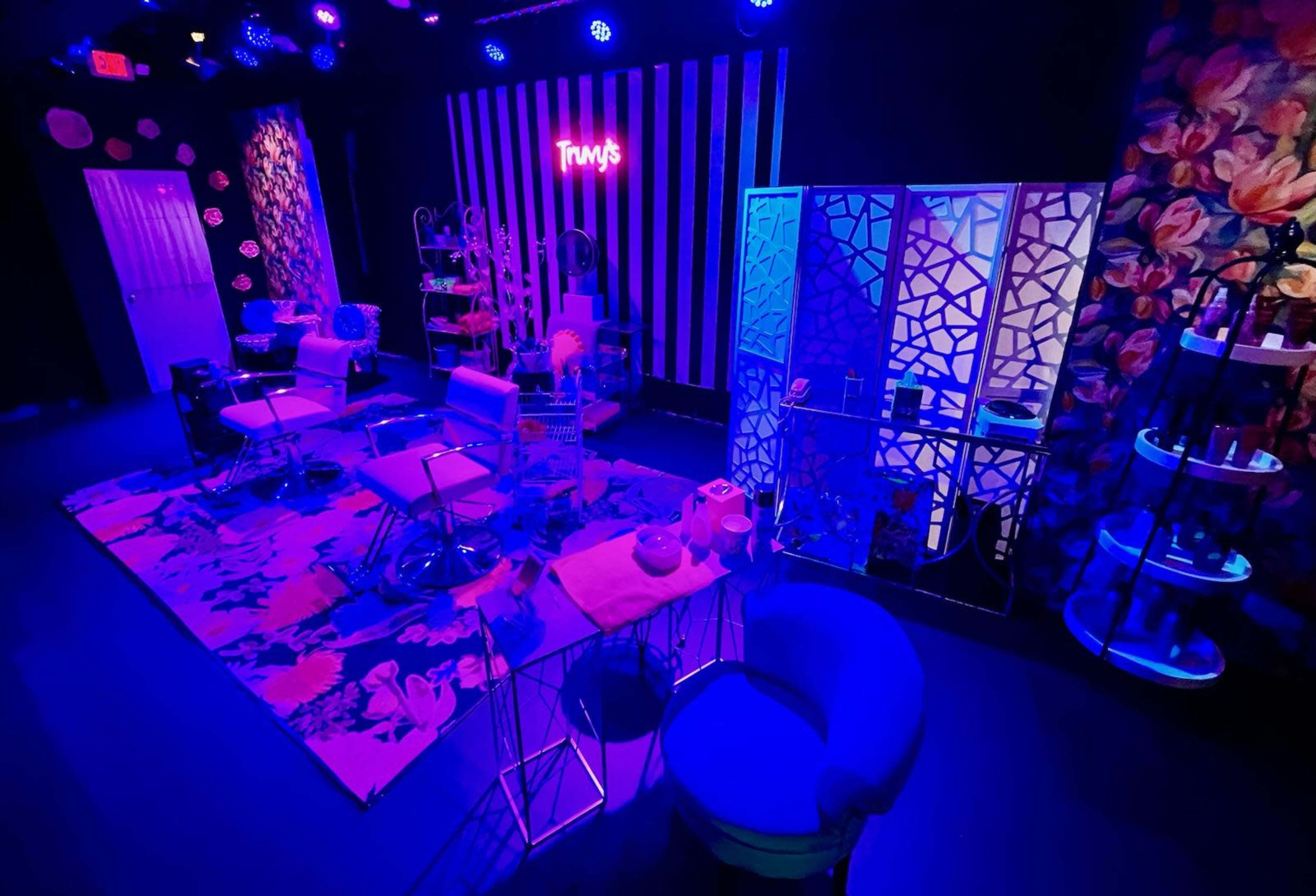 A brightly lit salon interior features modern furniture, colorful decor, and a vibrant floral rug.