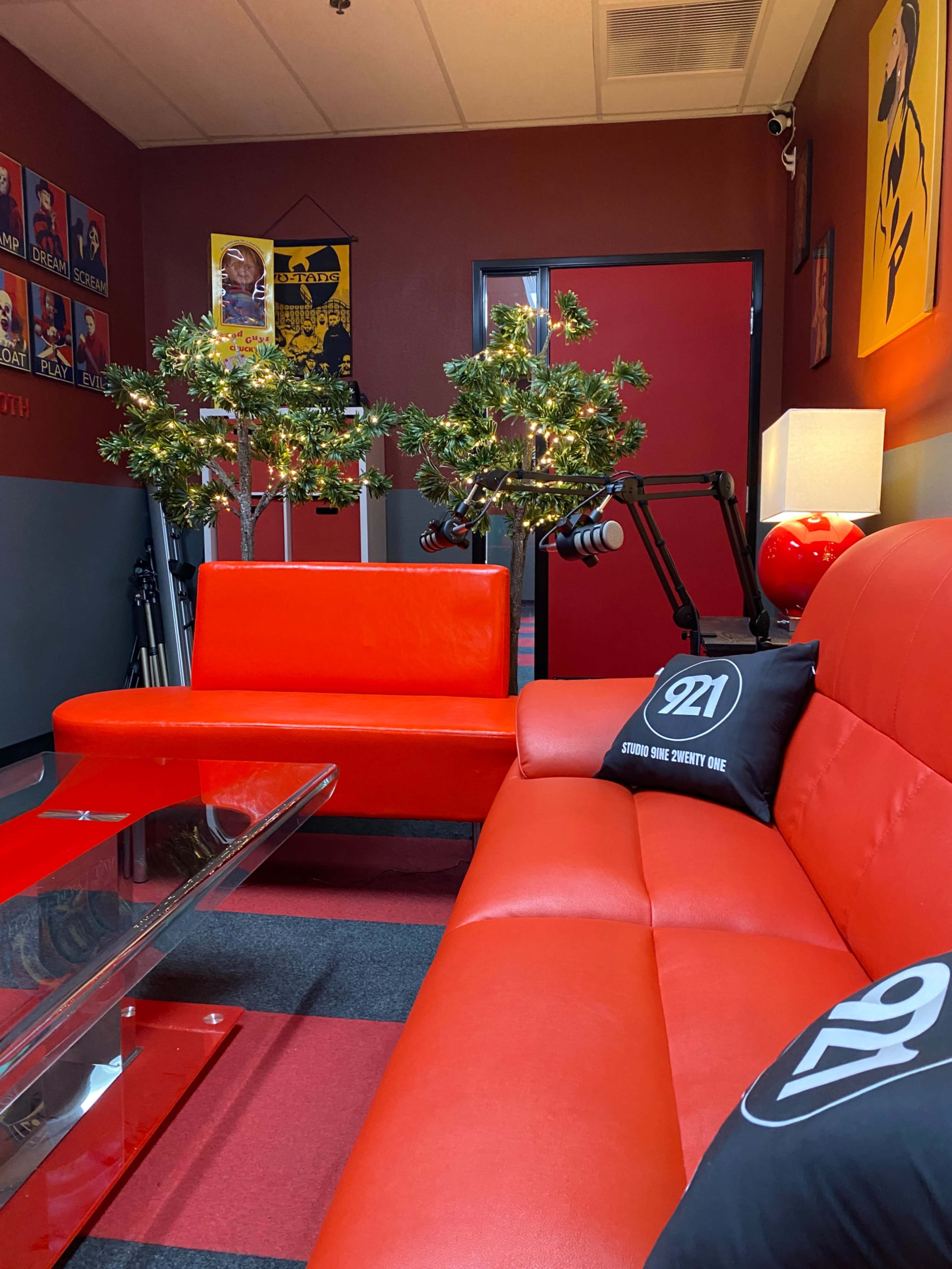The image shows a lounge area with red sofas, decorative trees with lights, and a glass coffee table.