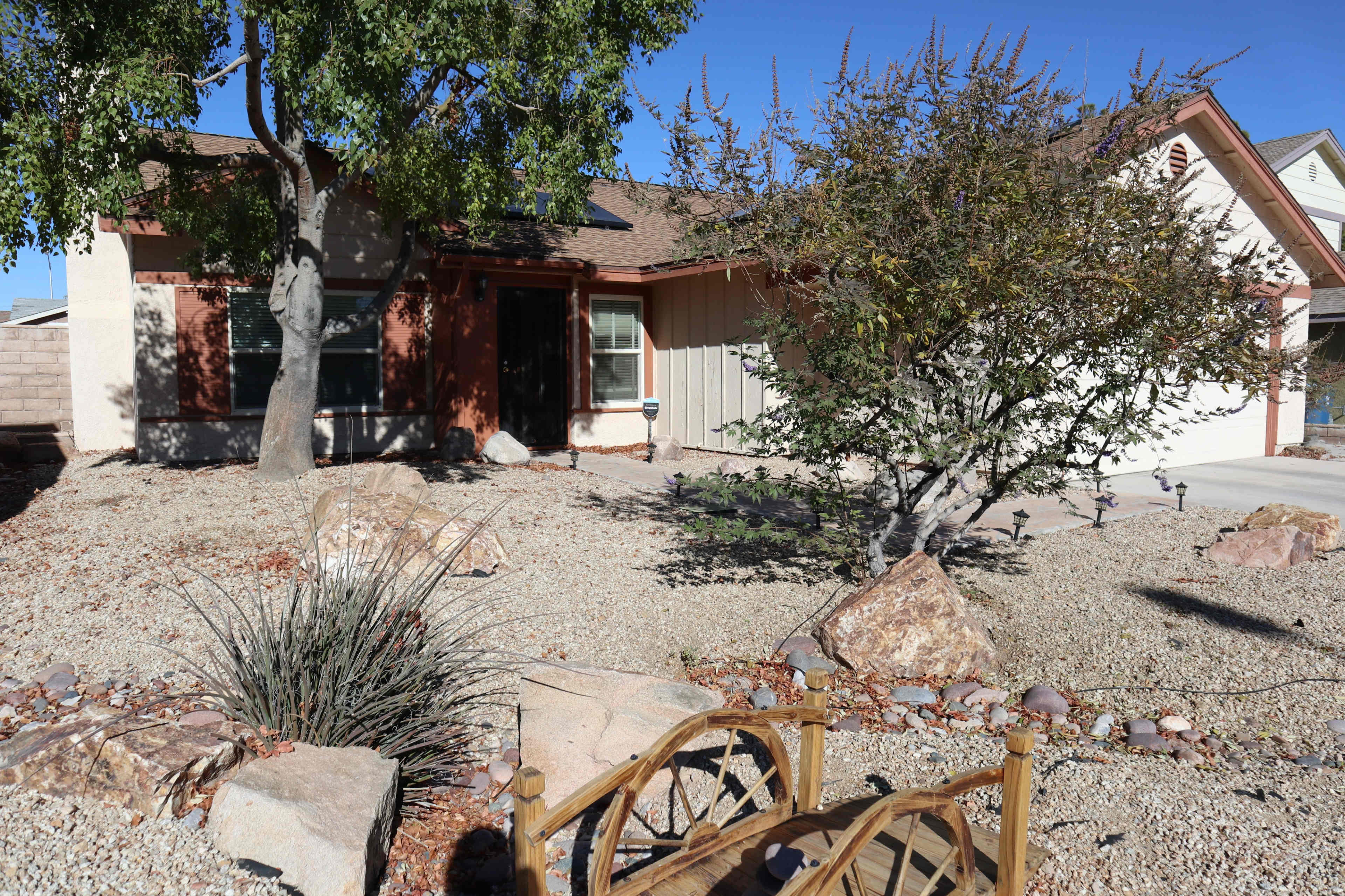 A single-story house surrounded by gravel landscaping, trees, and decorative rocks.