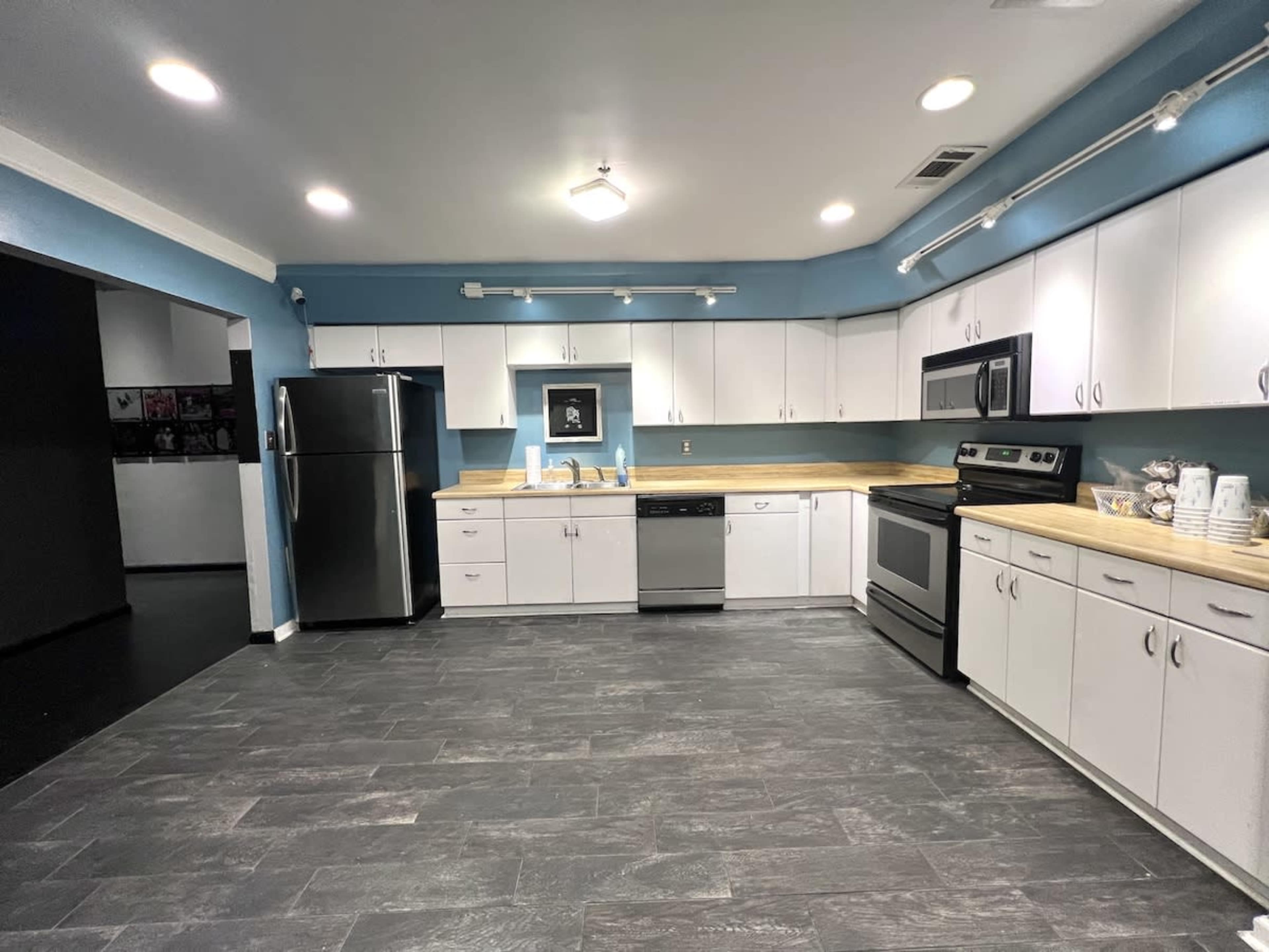 The image shows a modern kitchen with white cabinets, stainless steel appliances, and a blue accent wall.