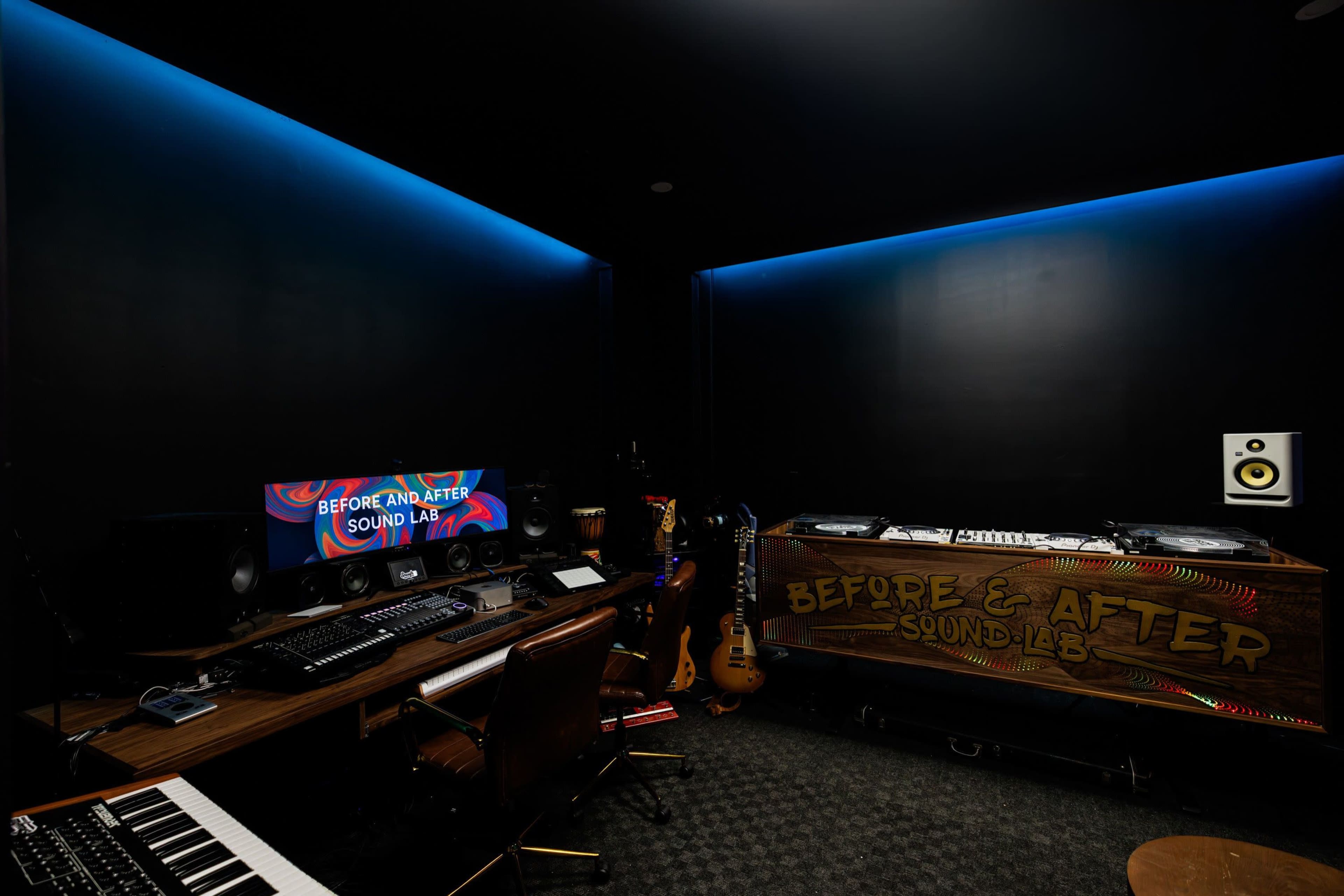 The image shows a modern sound studio featuring a desk with audio equipment, a computer, and a DJ setup on a wooden surface, along with musical instruments in the corner.