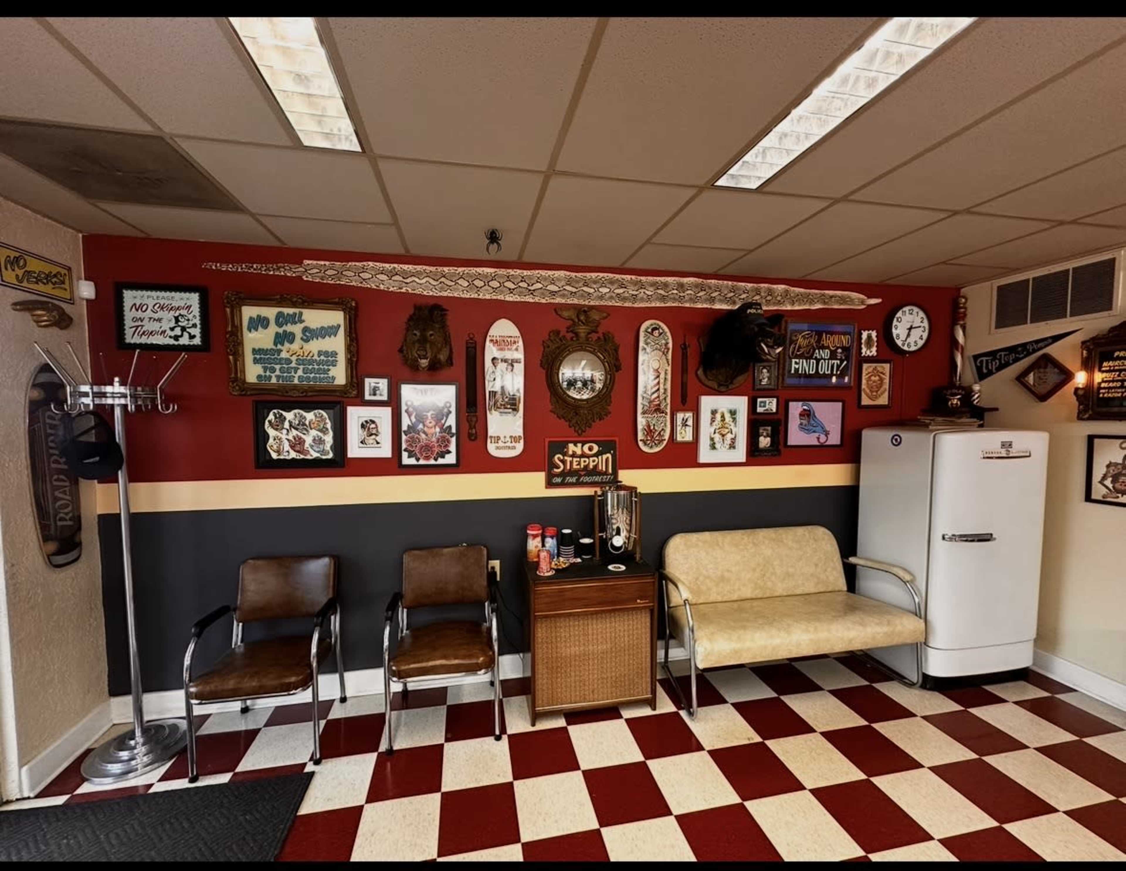 The image shows a vintage-themed waiting area with a patterned floor, three chairs, a small wooden table, and various framed decorations on the walls.