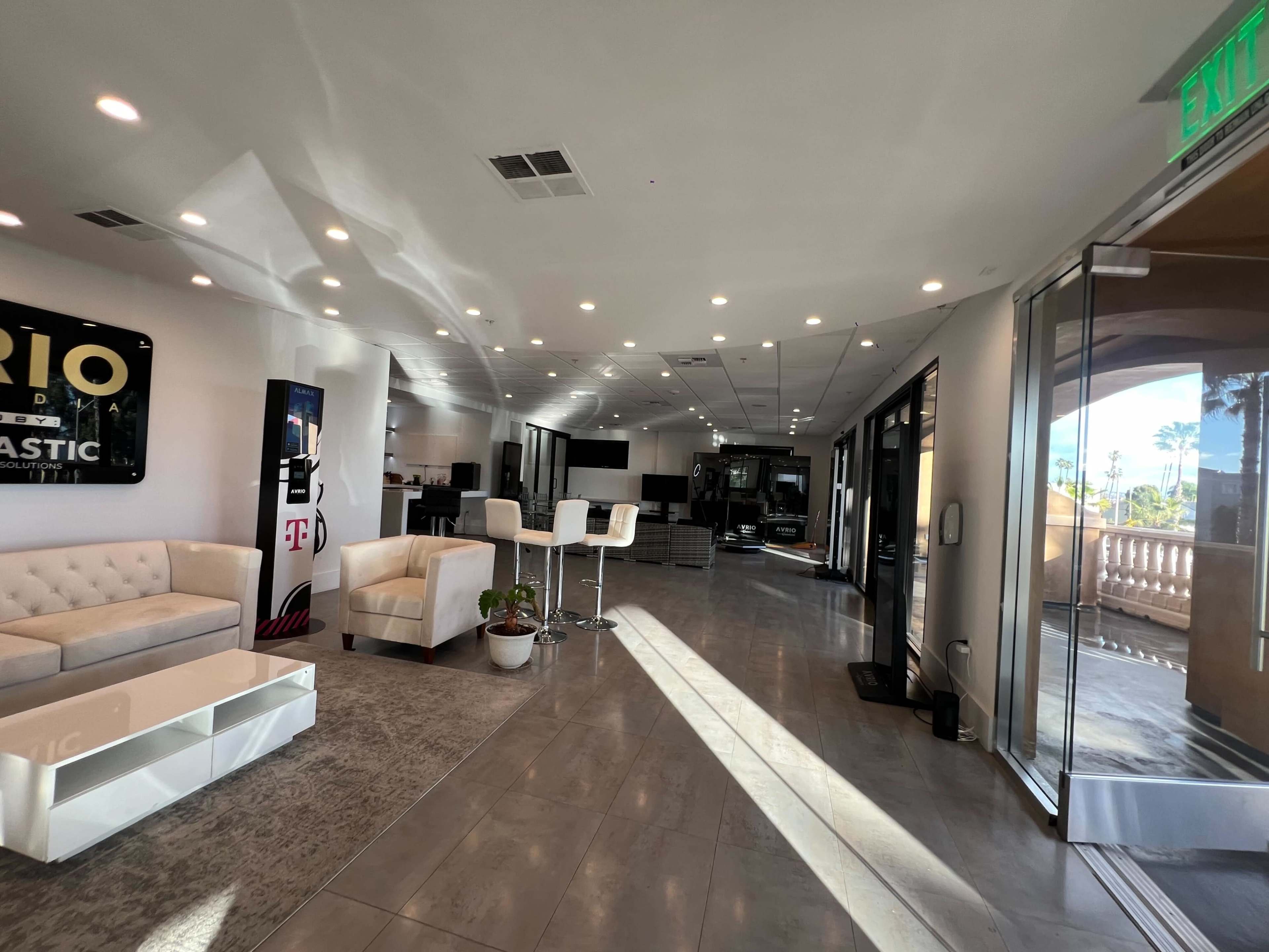 A modern, well-lit lobby area with a seating arrangement and large windows leading to an outdoor exit.