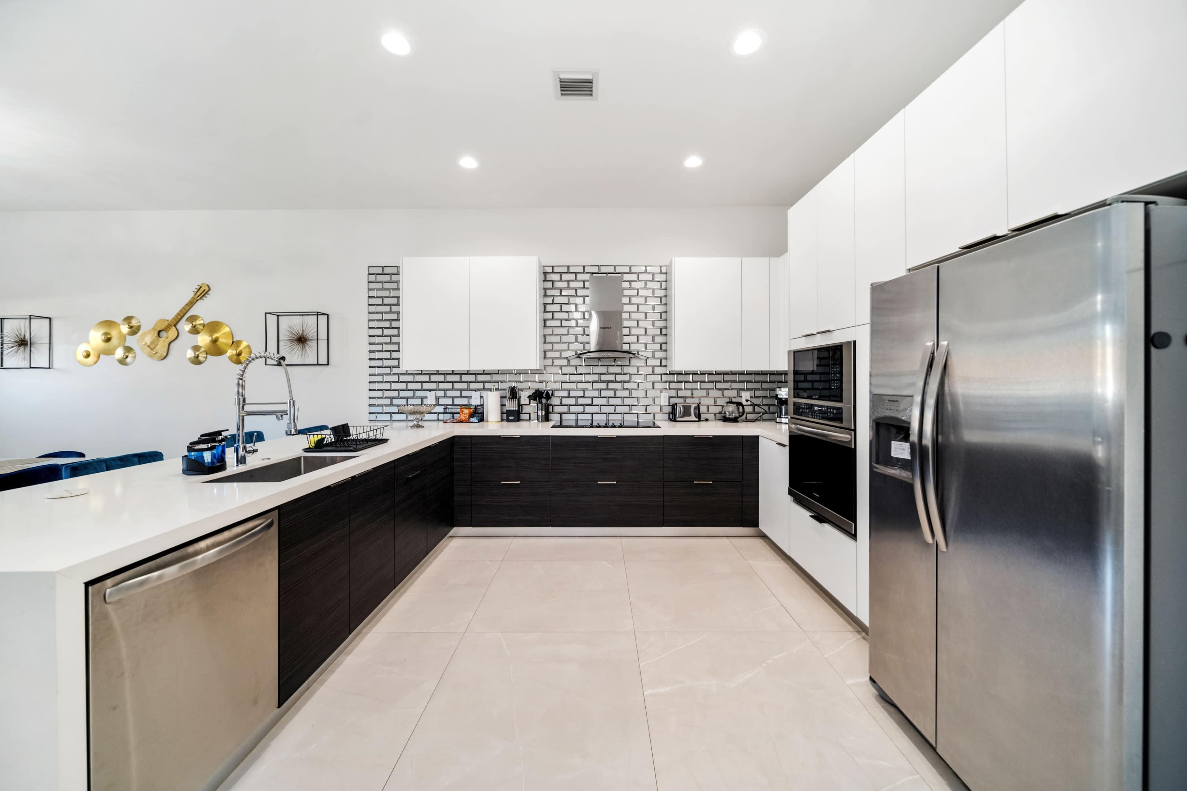 A modern kitchen with white cabinetry, a stainless steel refrigerator, and a tiled backsplash.
