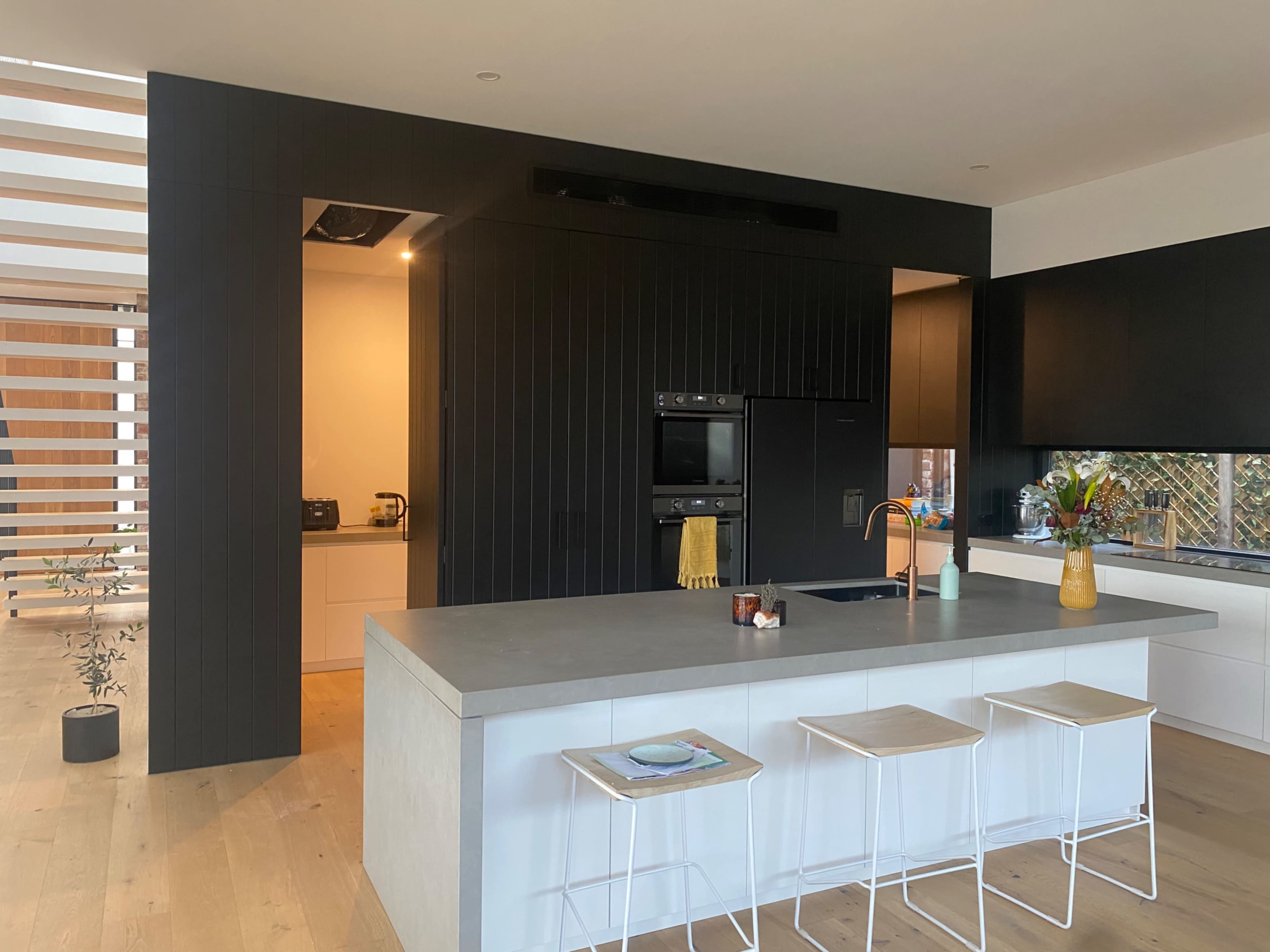 A modern kitchen with a gray countertop, black cabinetry, and an open layout featuring a dining area in the background.