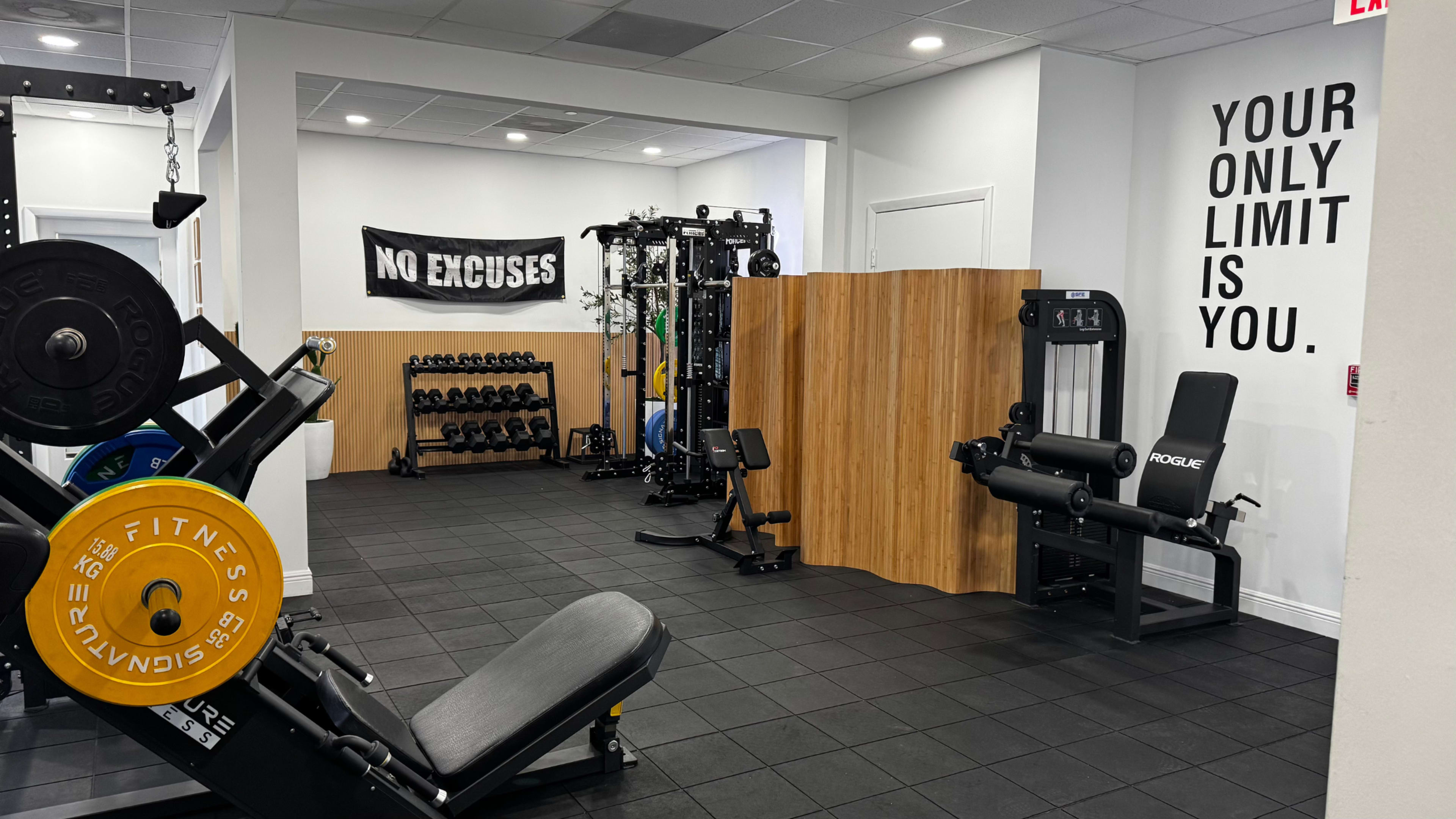 The gym features various workout equipment, including a weight bench and free weights, with motivational banners on the walls.